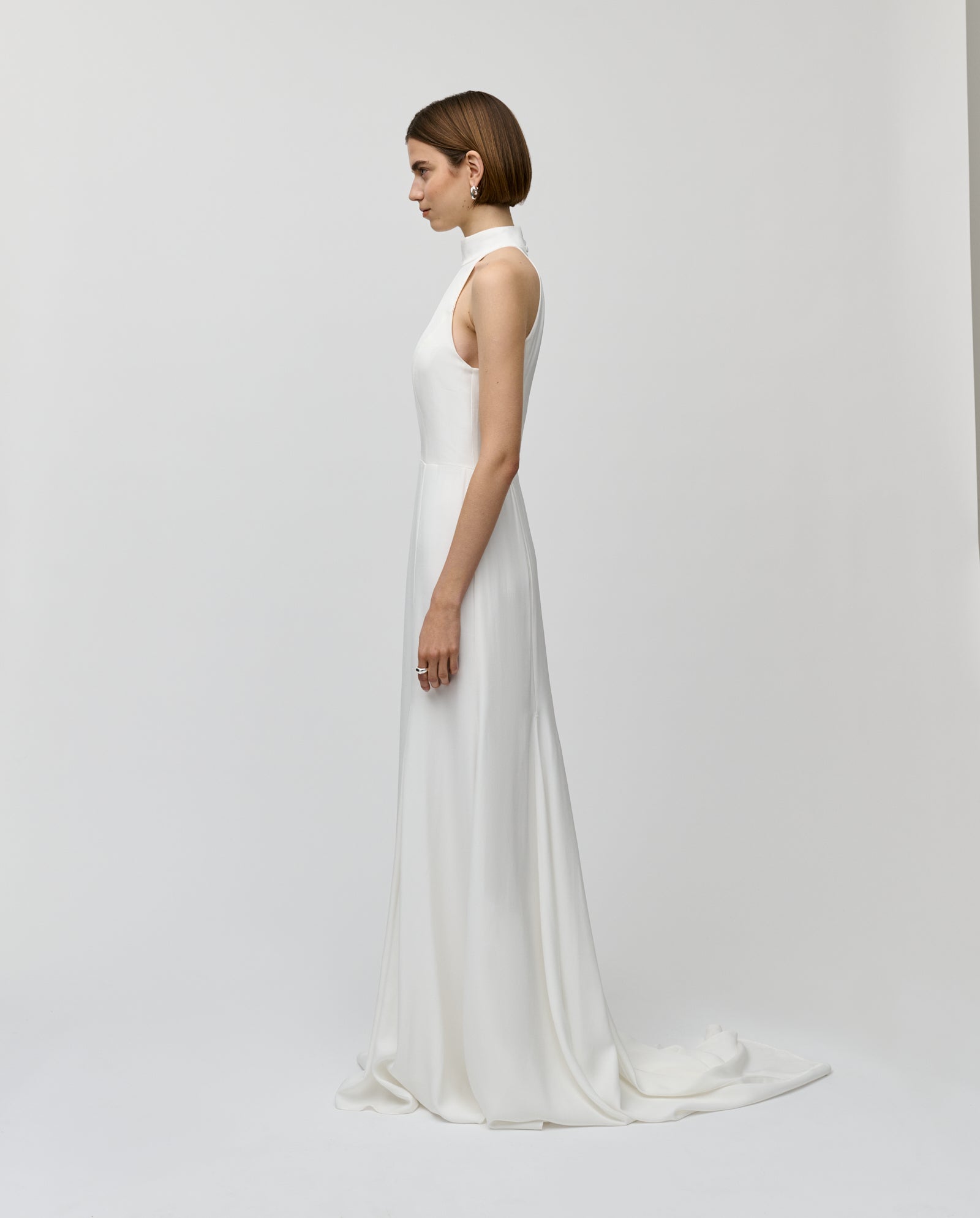 A woman models the IVY OAK MEREDITH sleeveless neck holder bridal maxi dress in profile against a plain white background.