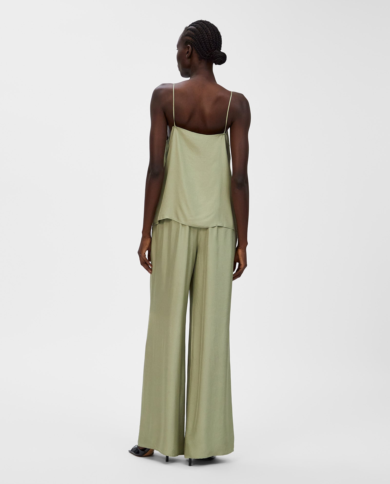 Woman wearing a loose, light green IVY OAK TILDA ANN Top with a V-neckline and matching wide-leg pants, shown from the back.