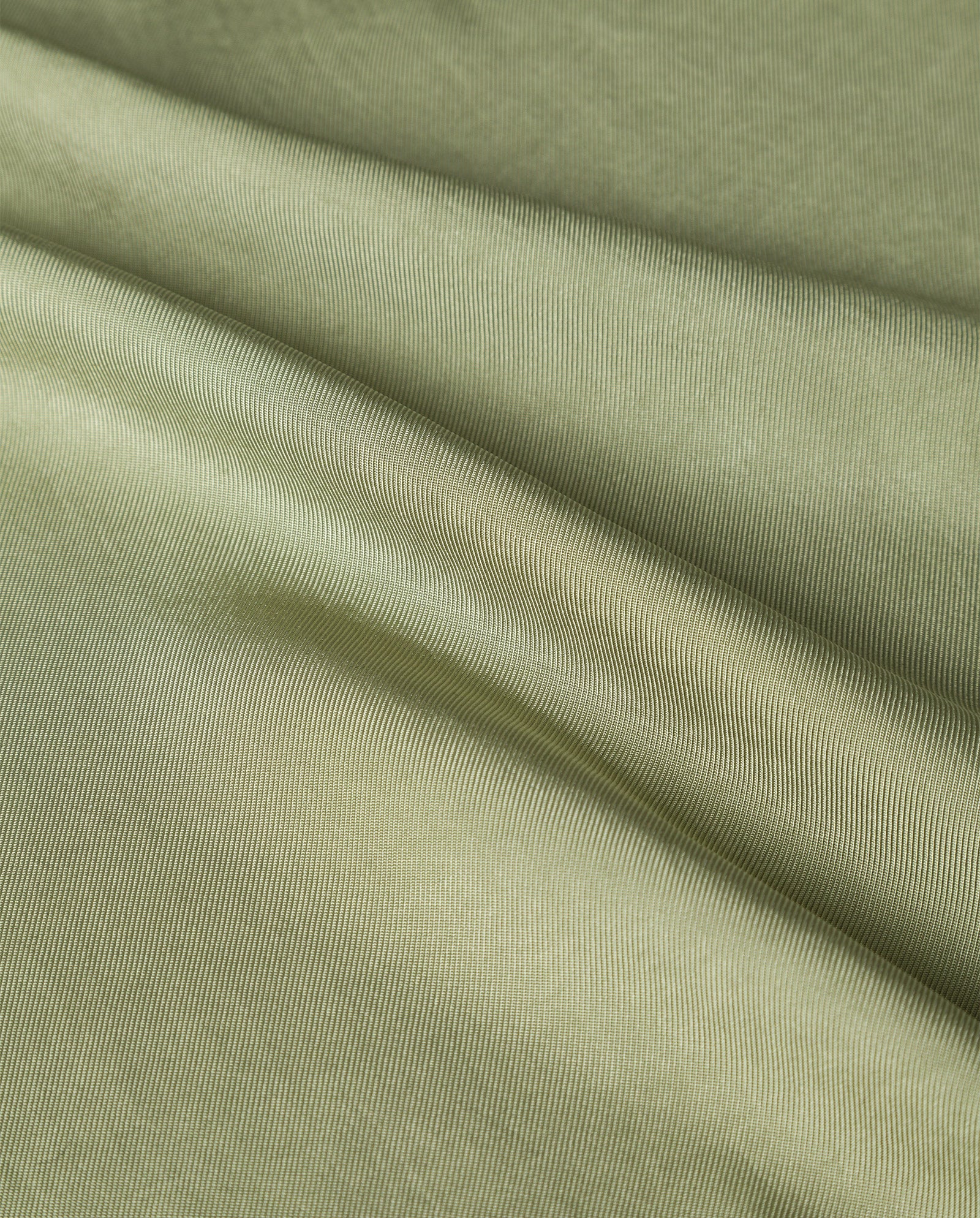 Close-up of the TILDA ANN Top by IVY OAK, crafted from light green, textured Naia acetate fabric with gentle folds and soft shadows.