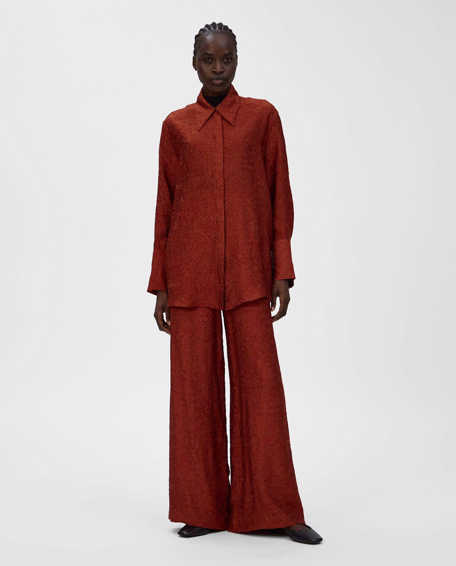 A person wears a loose-fitting, textured red ELVIE ANN Blouse by IVY OAK with a wide collar and matching wide-leg pants against a plain background, creating a striking monochrome look.