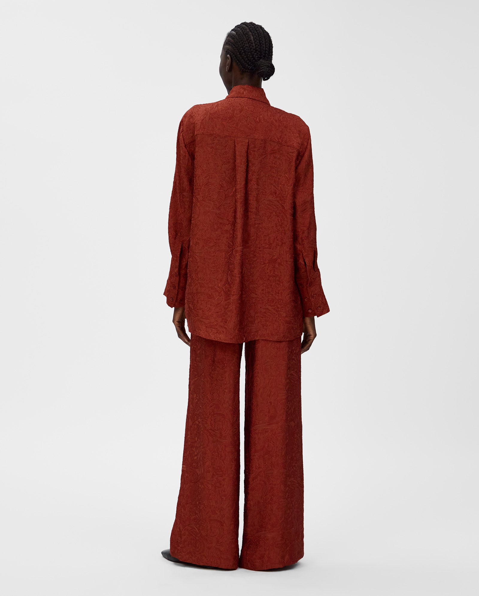A person is seen from the back wearing a loose, textured rust-colored IVY OAK ELVIE ANN blouse with a wide collar and matching wide-leg pants for a chic monochrome look.