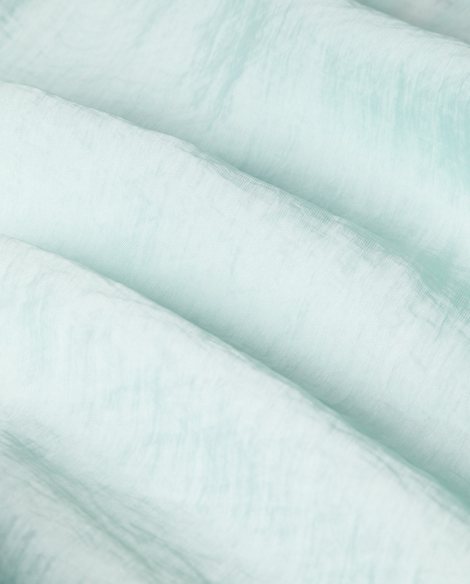 Close-up of the EBONEY Blouse by IVY OAK, crafted from light blue, semi-transparent organza fabric with elegant soft folds and a textured finish.