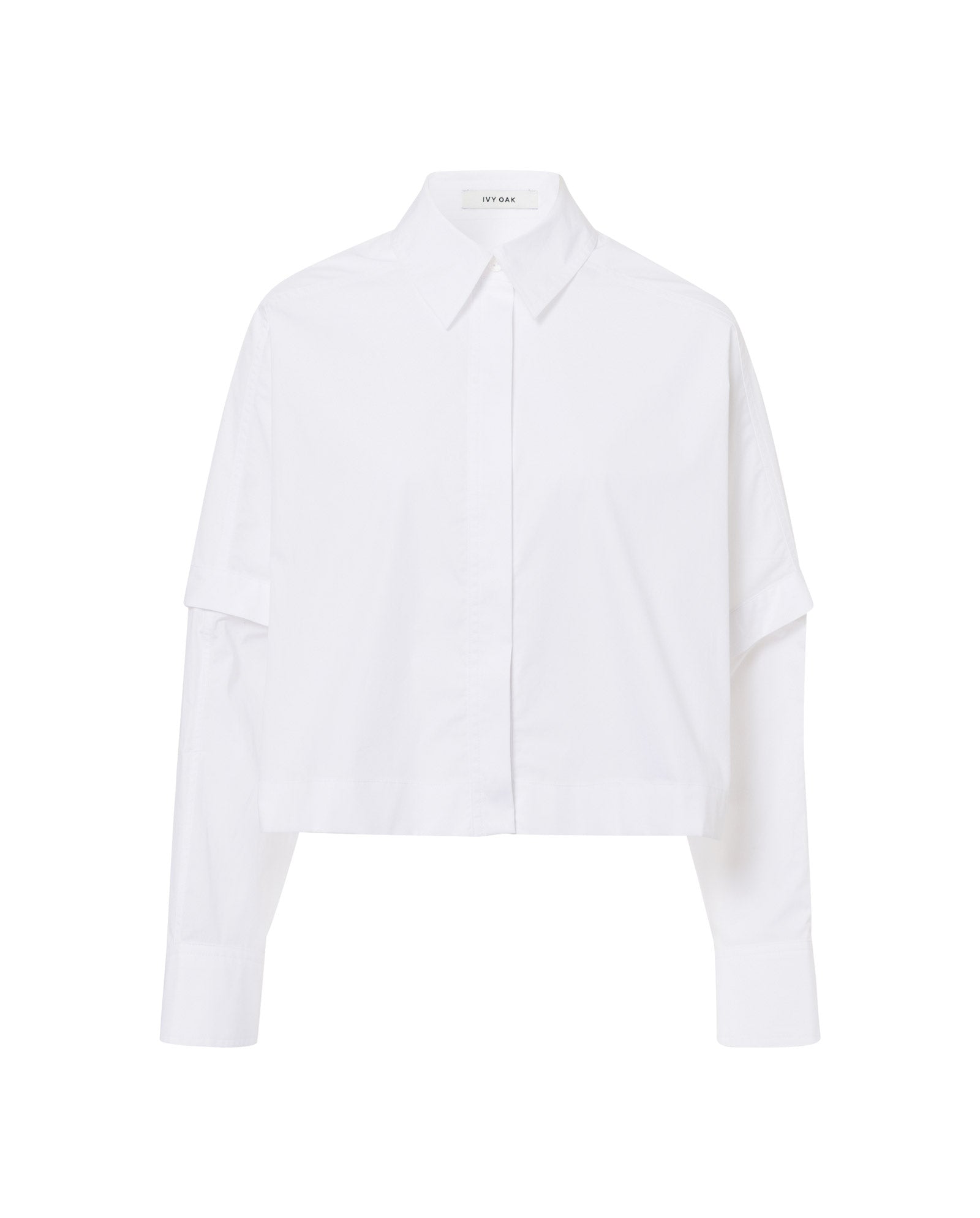 The IVY OAK ELVIRA Shirt is a white, long-sleeve, button-up blouse with a collar and a slightly cropped, boxy fit.