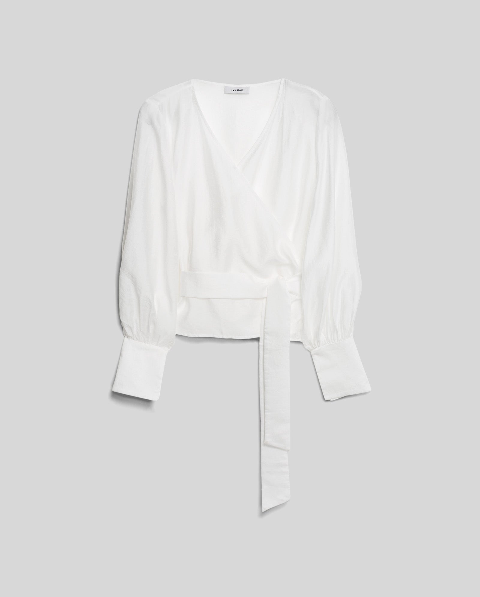 The IVY OAK ELOISE MAY Blouse is a white organza wrap top with long sleeves, extended cuffs, and a waist tie, shown on a plain gray background.