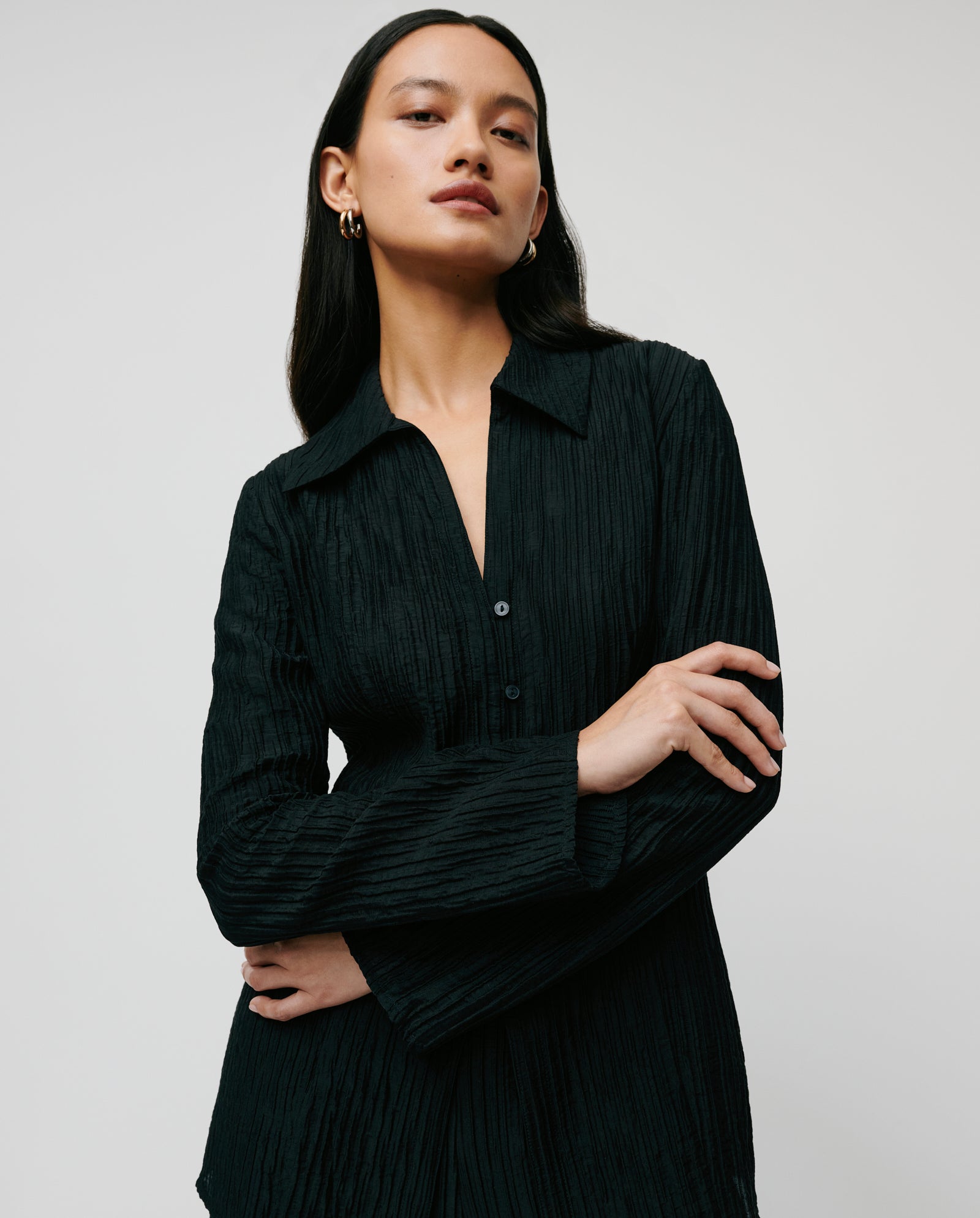 Woman wearing the IVY OAK EVELYN Blouse, featuring pleats and long sleeves, standing against a plain light background.