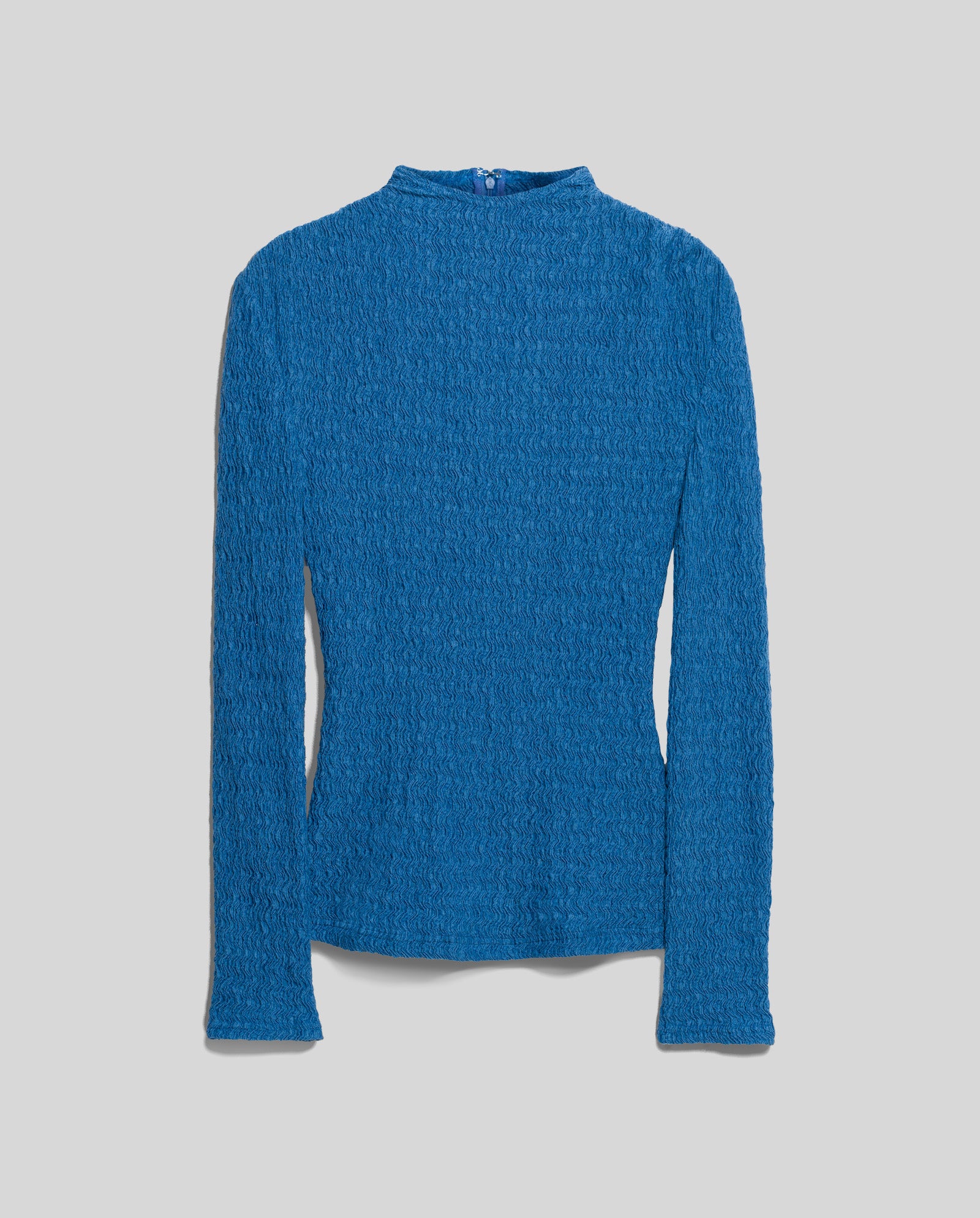 The IVY OAK TOSKA Top showcases a body-hugging fit and long sleeves, made from textured blue fabric with a mock neck, and is displayed laid flat on a light gray background.