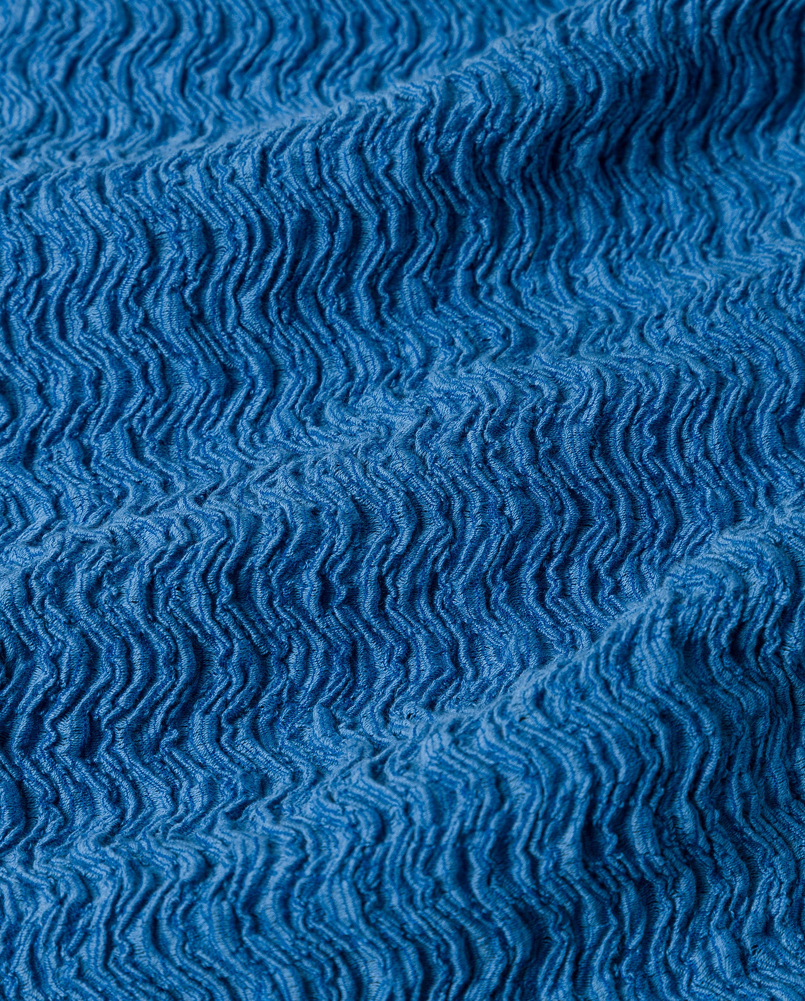 Close-up of the IVY OAK TOSKA Top’s textured blue fabric, highlighting its wavy, crinkled patterns and ridged surface for a distinctive, figure-flattering fit.