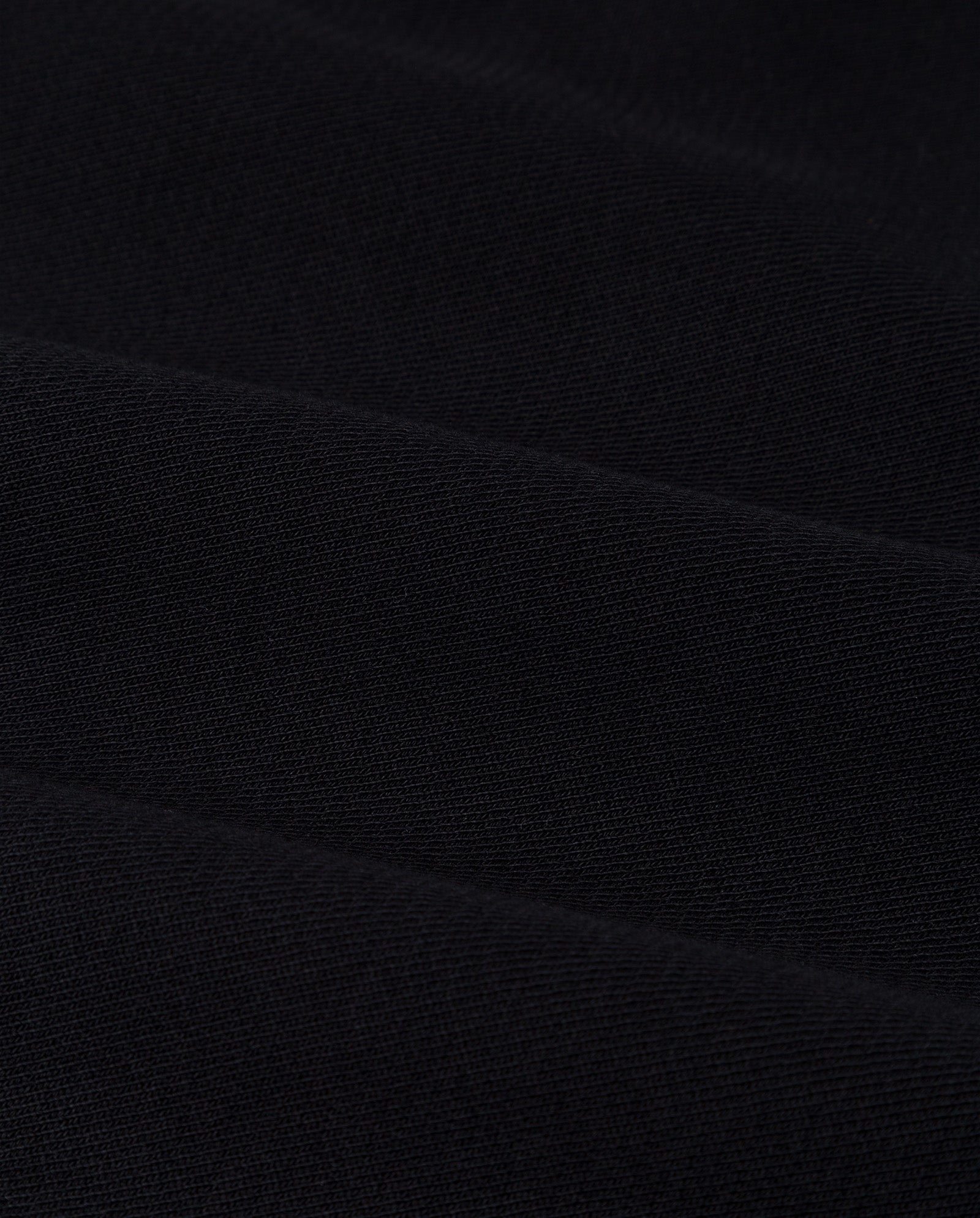 Close-up of black fabric with diagonal ribbed texture and soft folds, accentuating the oversized KAREN ROSE Jumper by IVY OAK—select a smaller size for a more fitted silhouette.