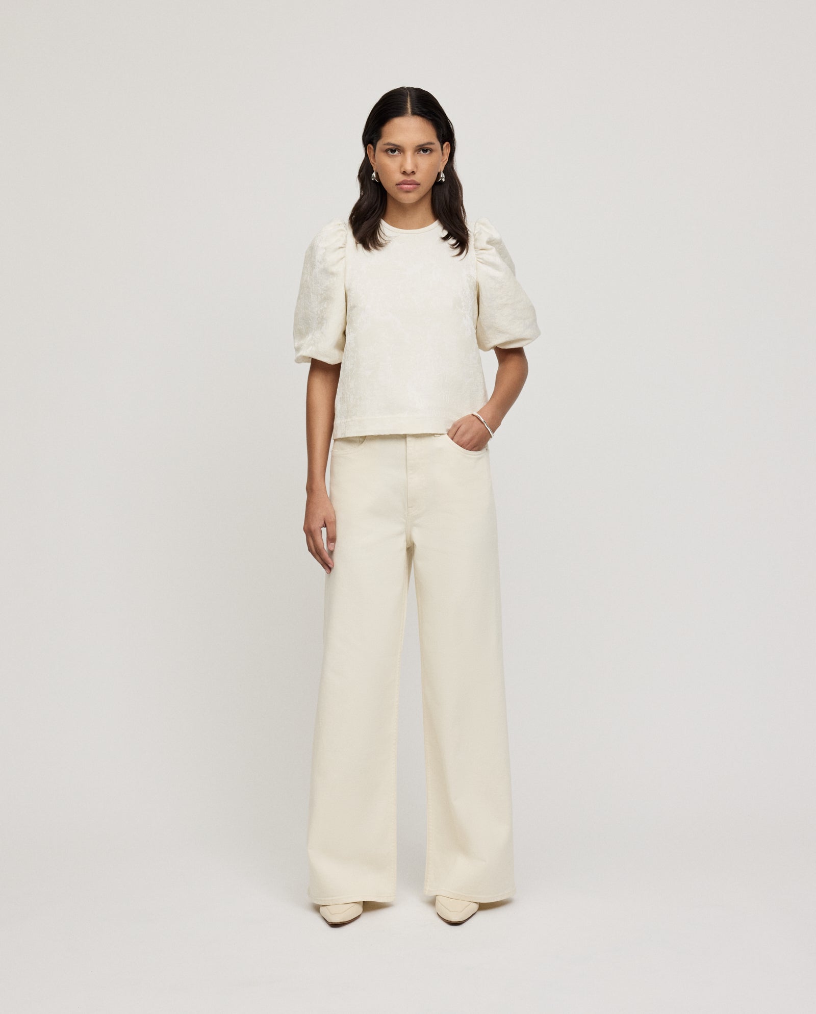 A woman wears the IVY OAK ELISABETH Top, featuring jacquard puff sleeves, paired with wide-leg pants against a plain white background.