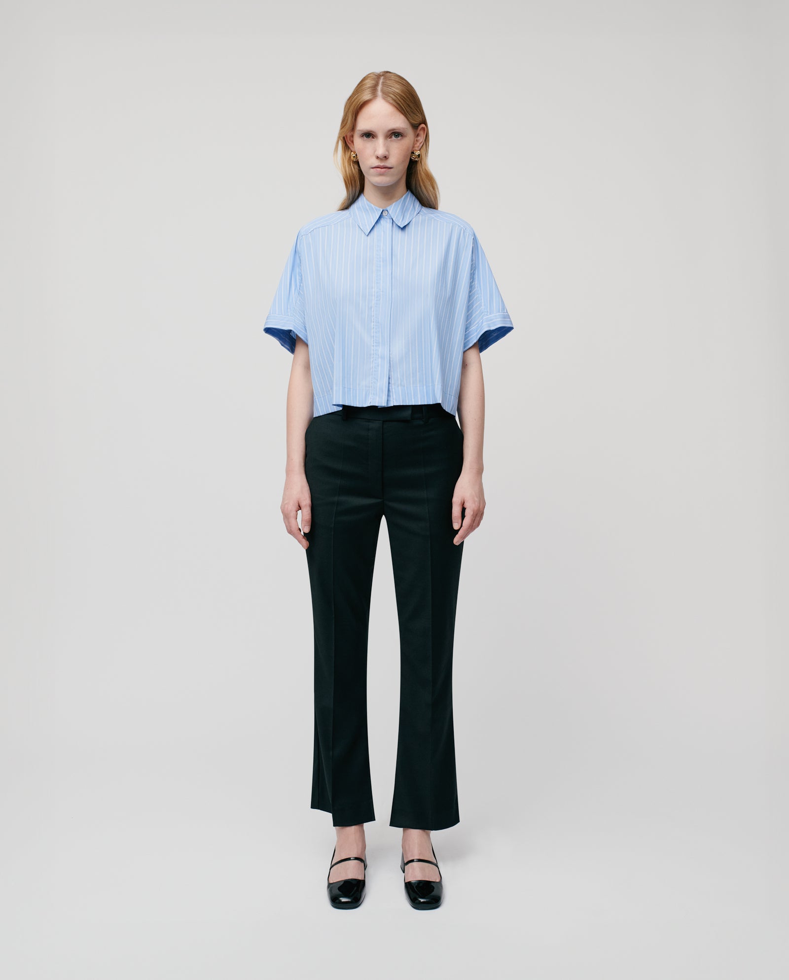 A woman wears the IVY OAK ELVIRA Blouse with detachable sleeves and black pants, standing against a plain white background.