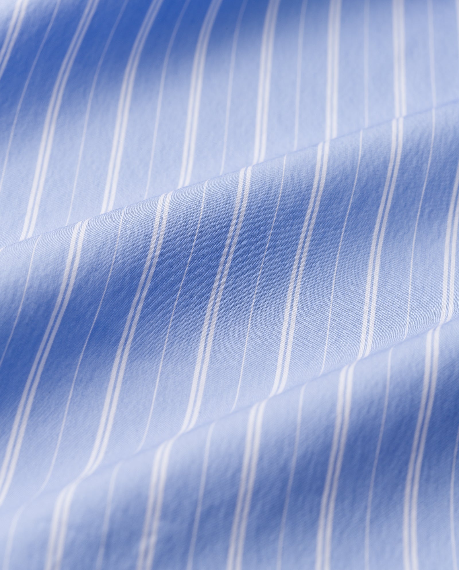 Close-up of light blue fabric with thin white vertical stripes and soft, wavy folds from the IVY OAK ELVIRA Blouse, ideal for cropped shirts or styles with detachable sleeves.