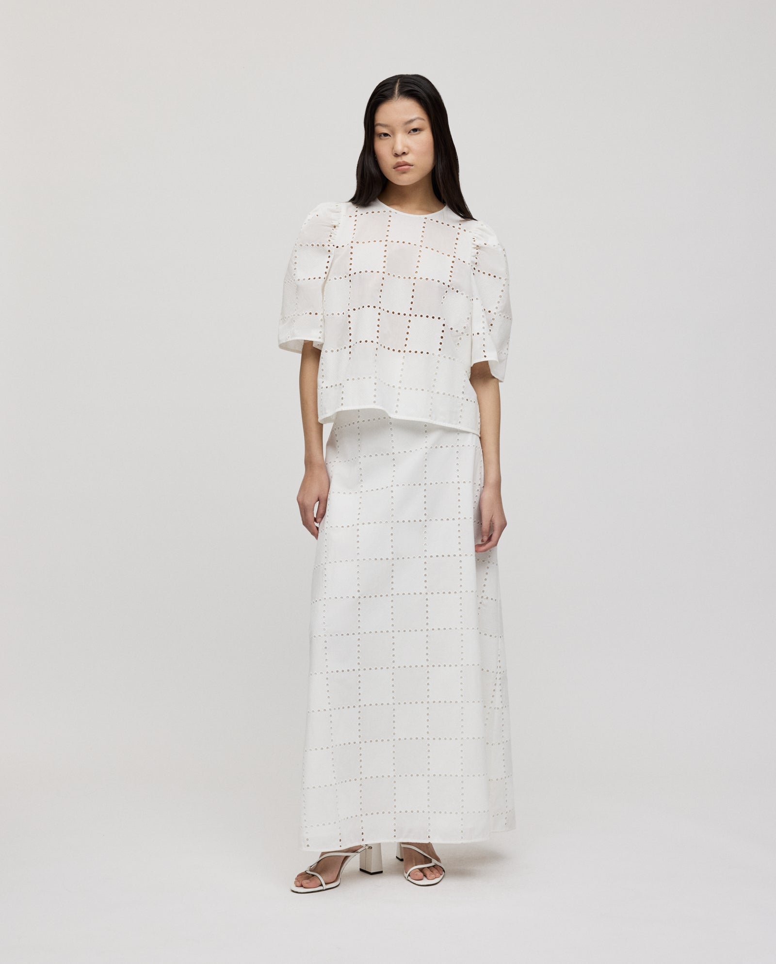 A woman wears the IVY OAK ELISABETH ANN Top, a white loose-fit blouse with gathered sleeves, paired with a matching long skirt, on a white background.