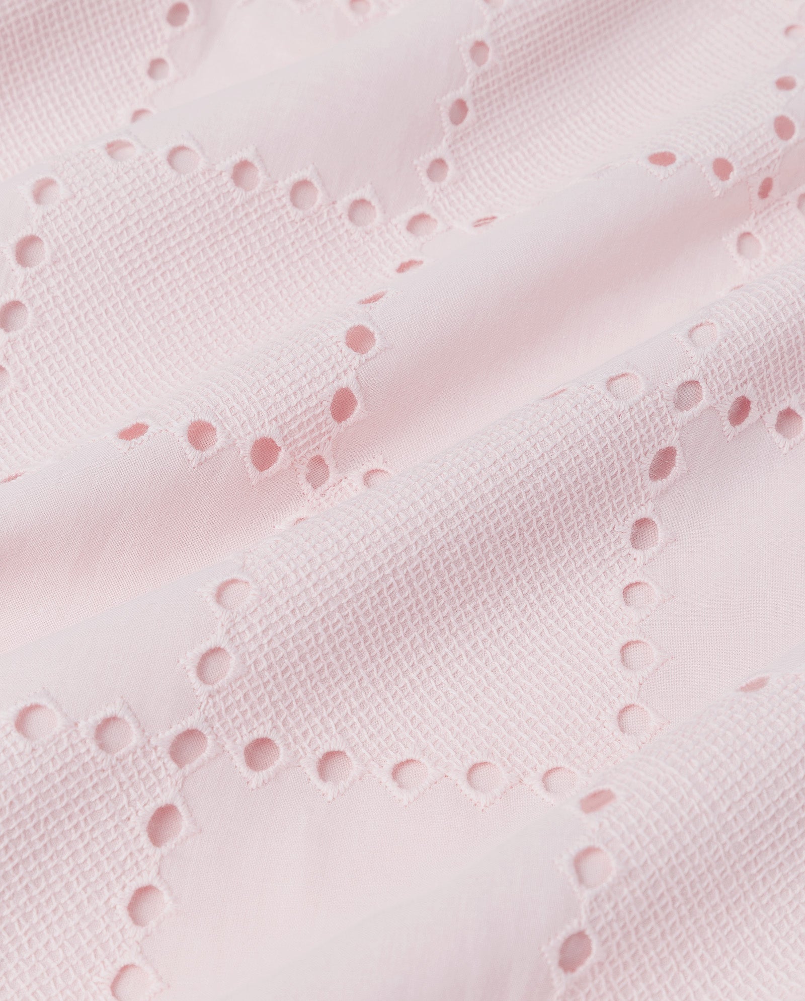 The TALA Top by IVY OAK features light pink fabric with a textured grid pattern and decorative anglaise eyelet embroidery in diagonal lines—ideal for a breezy, sleeveless look.