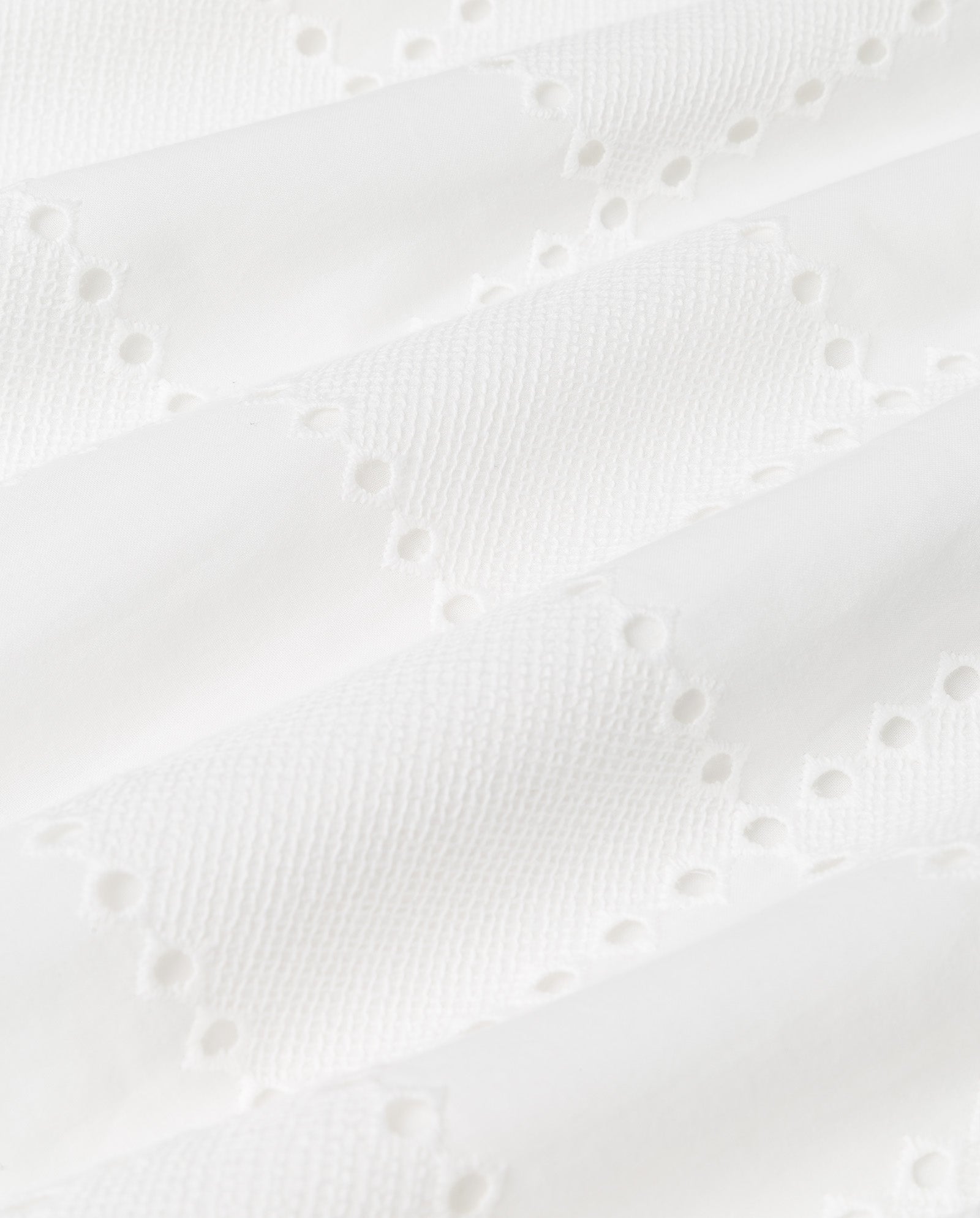 White textured fabric with embroidered anglaise eyelet patterns and small holes in rows, ideal for the sleeveless IVY OAK TALA Top.