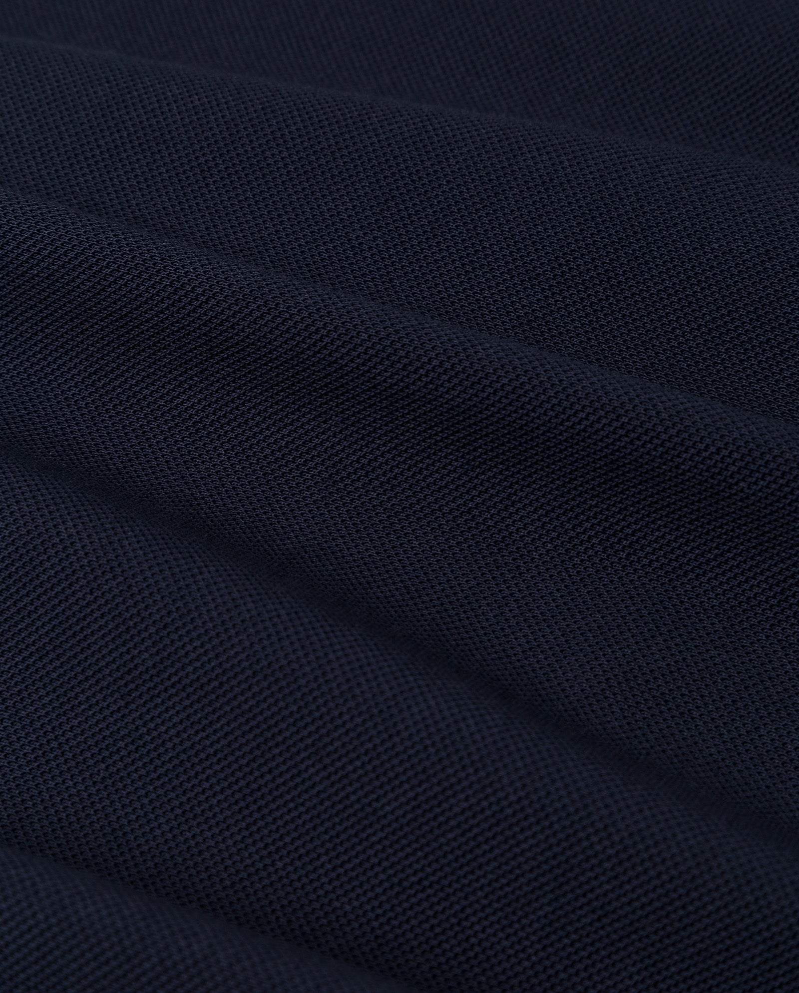 Close-up of the FABIOLA Top by IVY OAK in dark navy blue organic cotton, showing its textured weave and soft diagonal folds—perfect for a premium look.