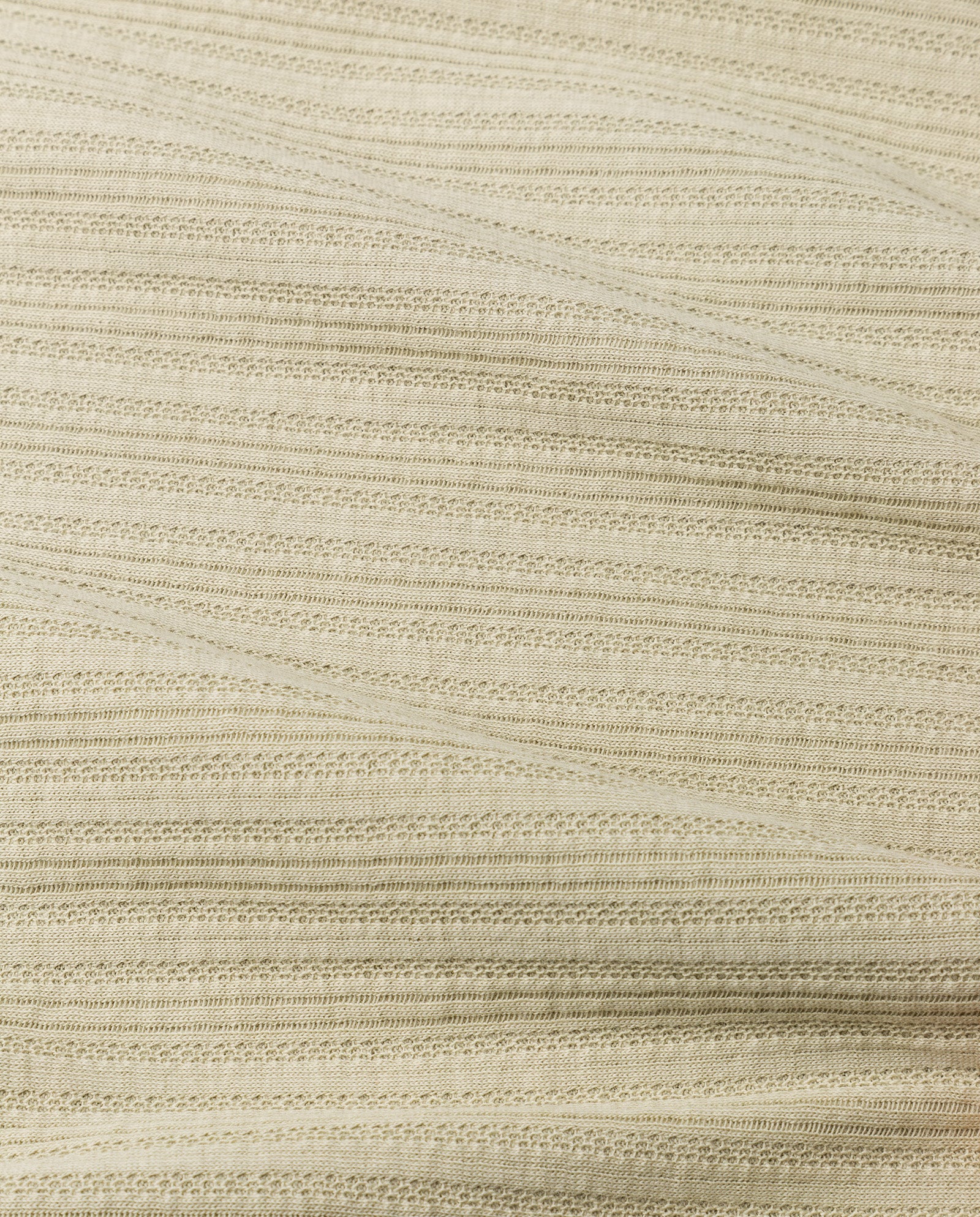 Close-up of the KAMILLE Cardigan by IVY OAK in beige cotton jersey, featuring horizontal, slightly wavy textured lines and a subtle striped pattern.