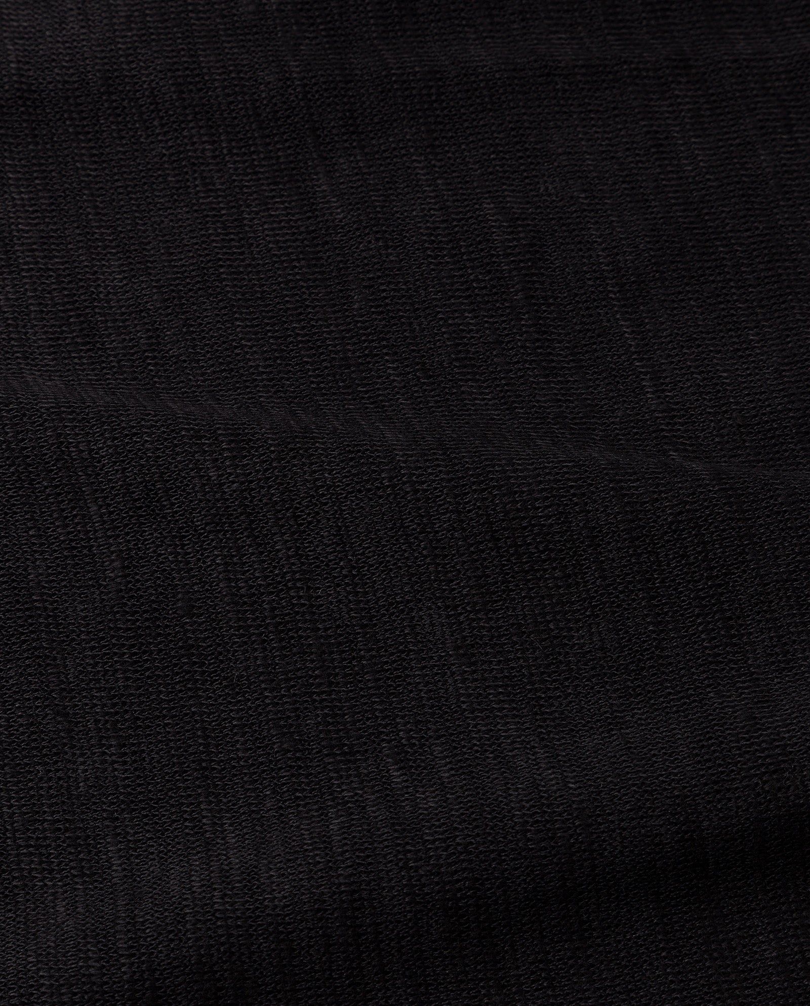 Close-up of the FELINE Top by IVY OAK, showing its black textured fabric with subtle woven lines and a slightly matte finish, characteristic of refined Mélange Jersey.