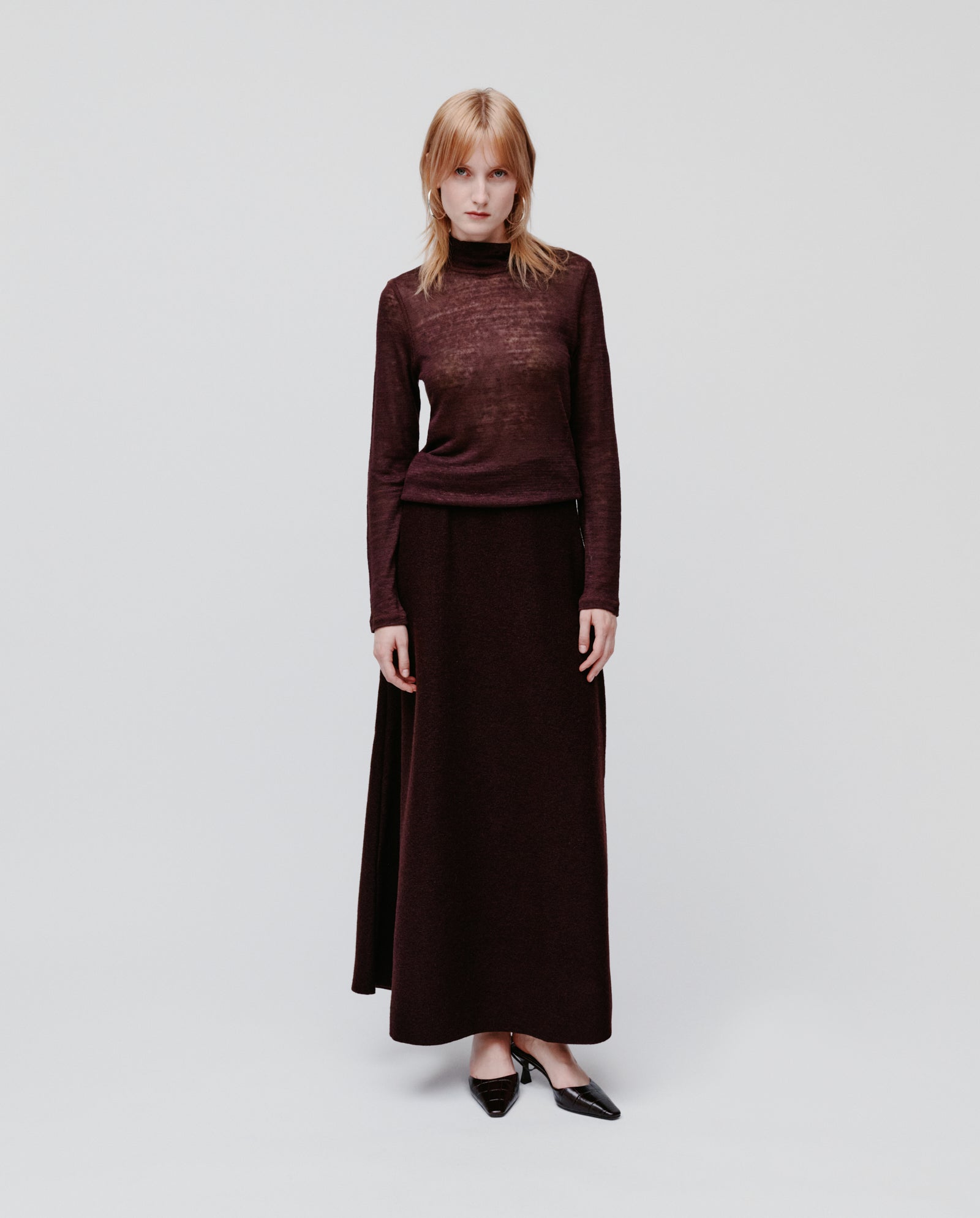 A woman wears the IVY OAK FELINE Top, a dark burgundy linen-blend jumper with long sleeves, paired with a matching long skirt, standing against a plain white background.