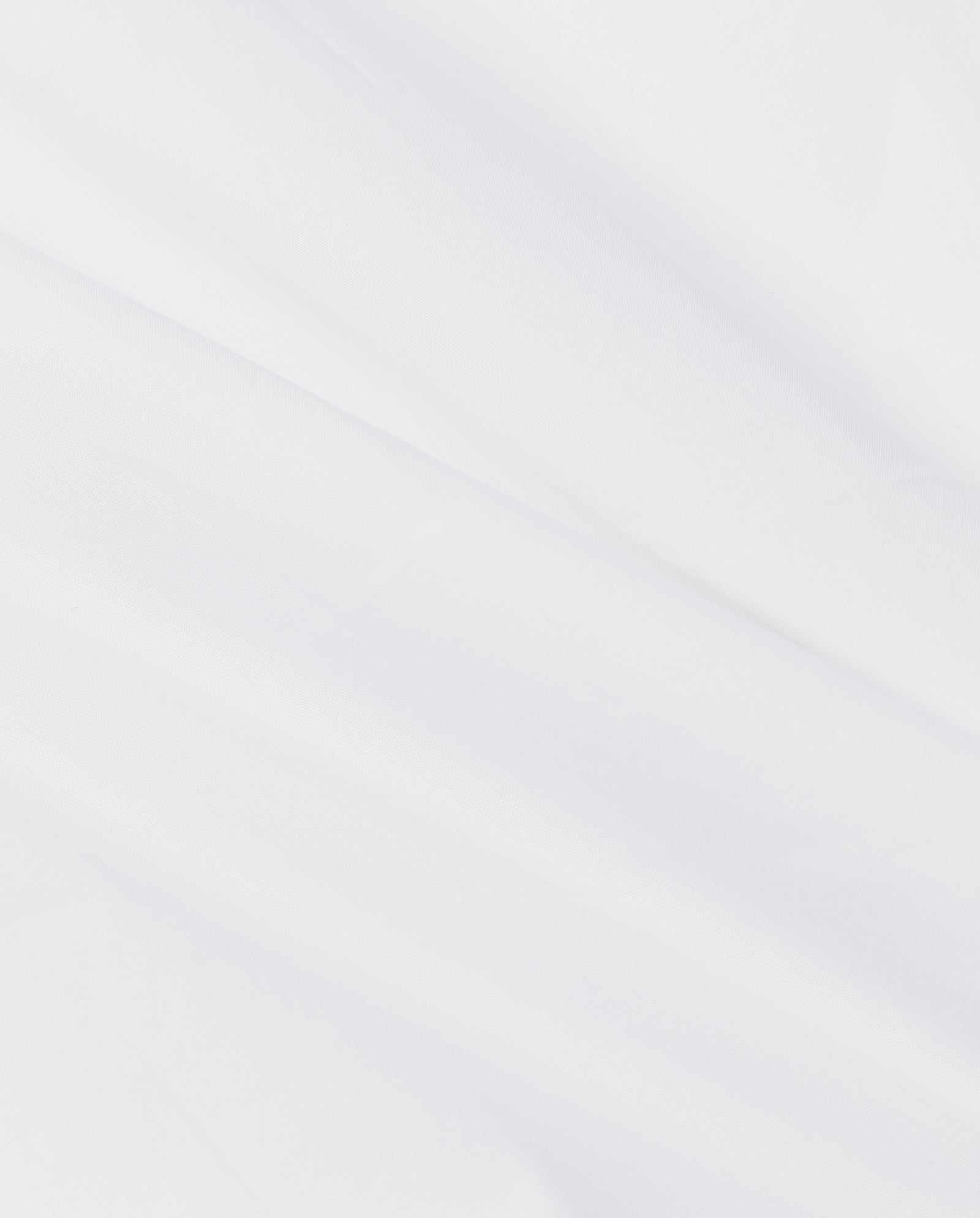 The EMORY Blouse by IVY OAK features white cotton poplin fabric with soft diagonal folds and subtle texture, creating gentle shadows and highlights.