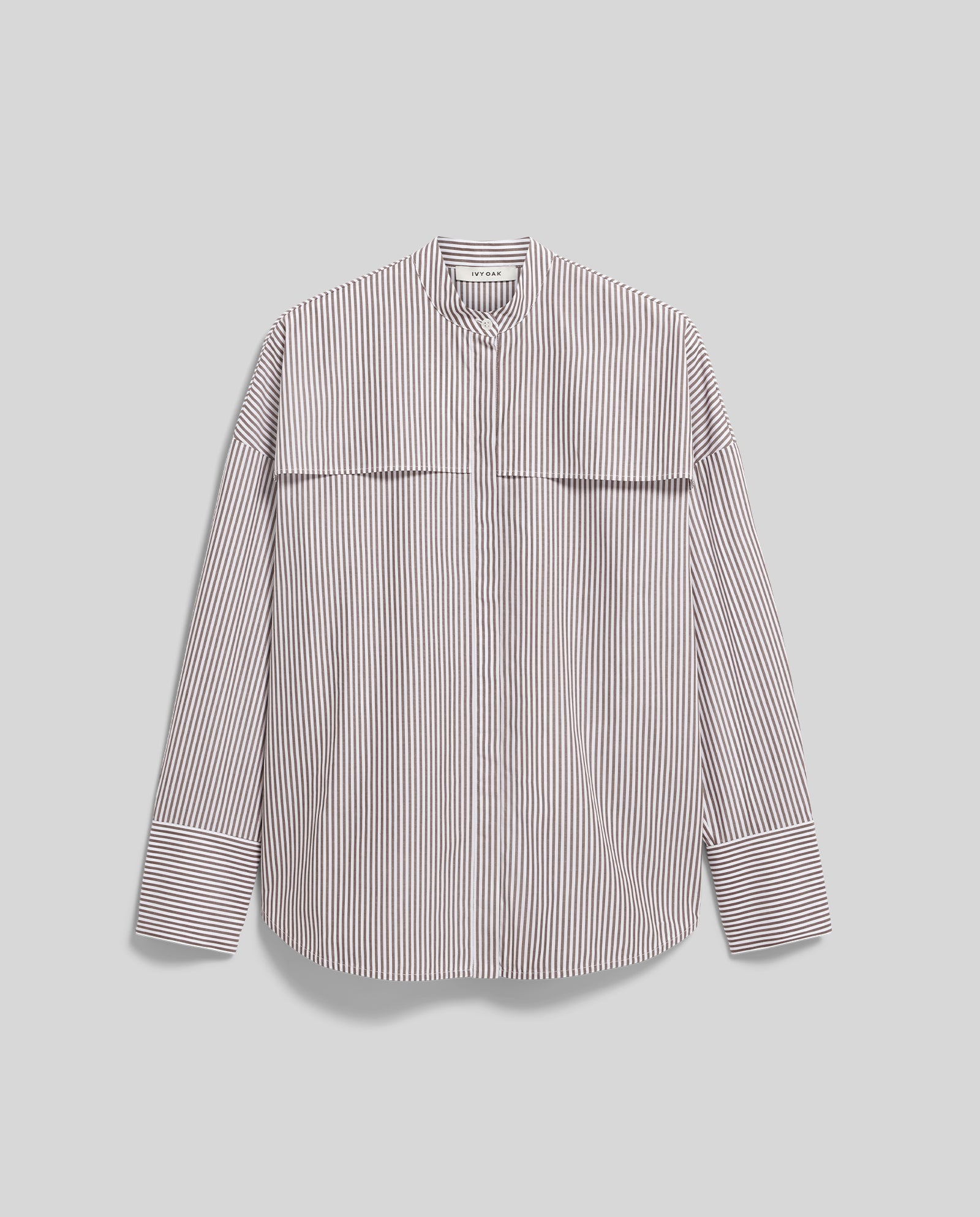 The EVE Blouse by IVY OAK features an oversized fit, long sleeves, vertical black and white stripes, a stand collar, and button closure. Displayed flat for a clear view of its stylish details.