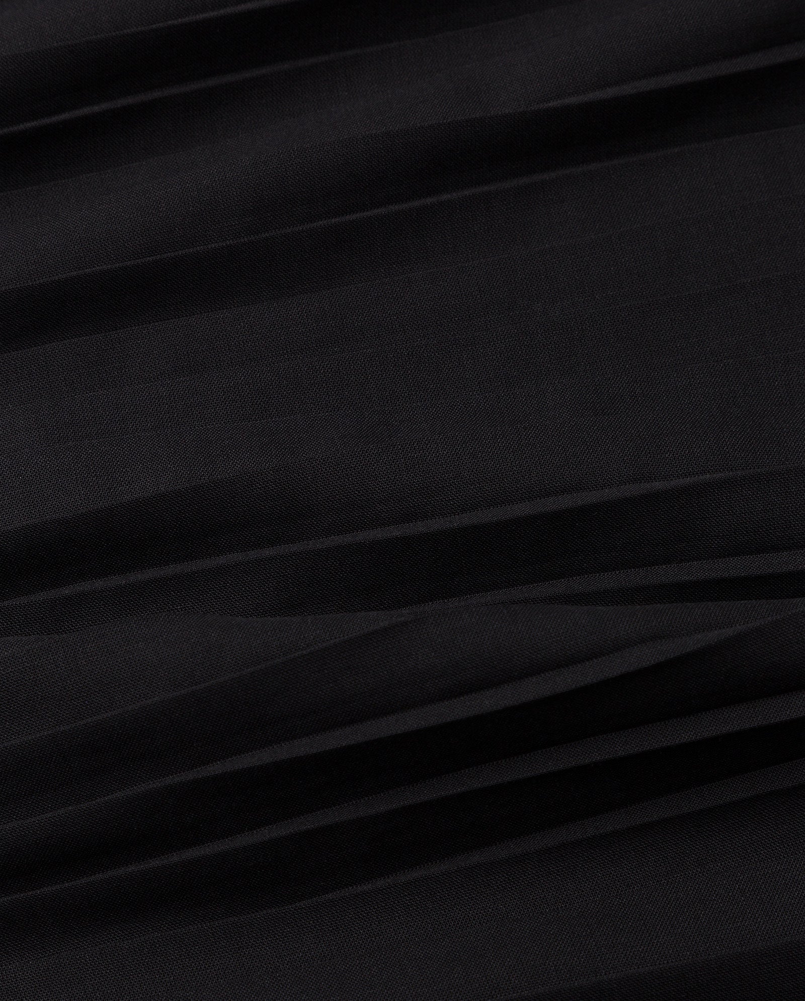 Close-up of black plissé fabric with soft, horizontal creases, echoing the elegant texture seen in the IVY OAK TAYE Top.