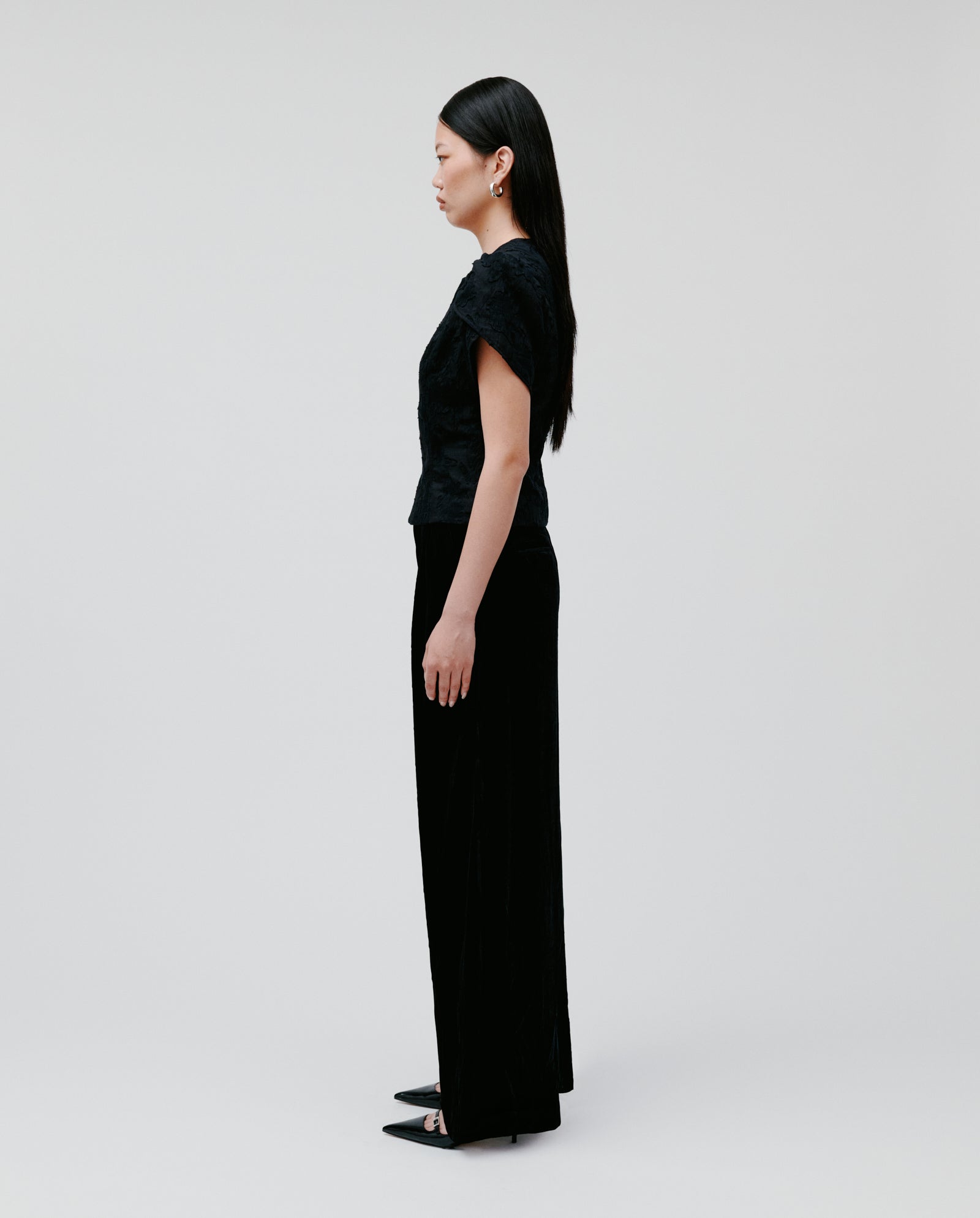 Woman with long dark hair wears the IVY OAK ELODIE Blouse, featuring voluminous sleeves, standing in profile against a plain light background.