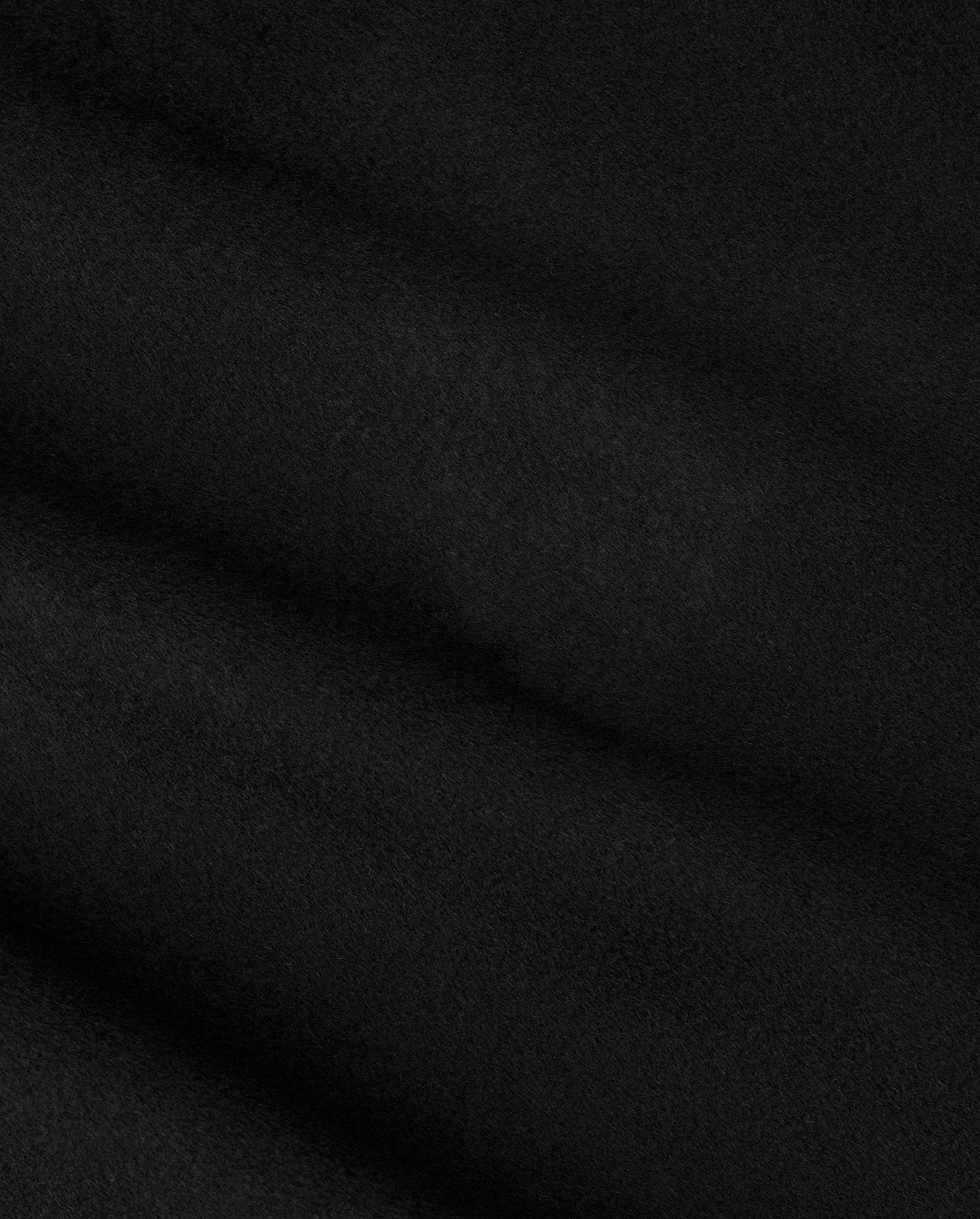 A close-up of the IVY OAK CARRIE ROSE Wool Coat’s minimalistic, smooth black fabric with subtle diagonal folds, highlighting its premium quality.