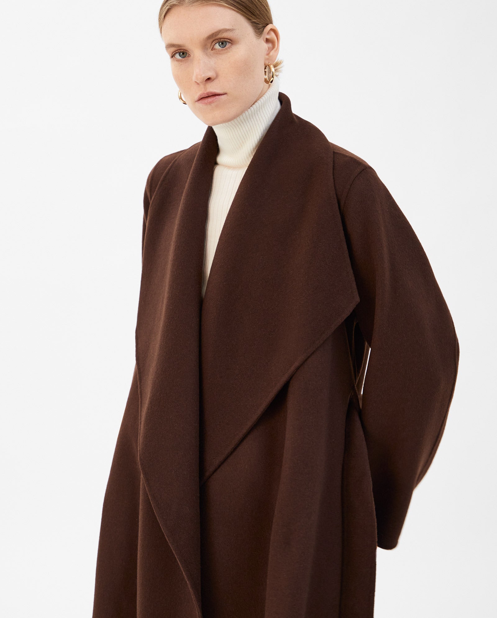 A woman stands against a plain white background wearing the IVY OAK CARRIE ROSE Wool Coat over a white turtleneck.