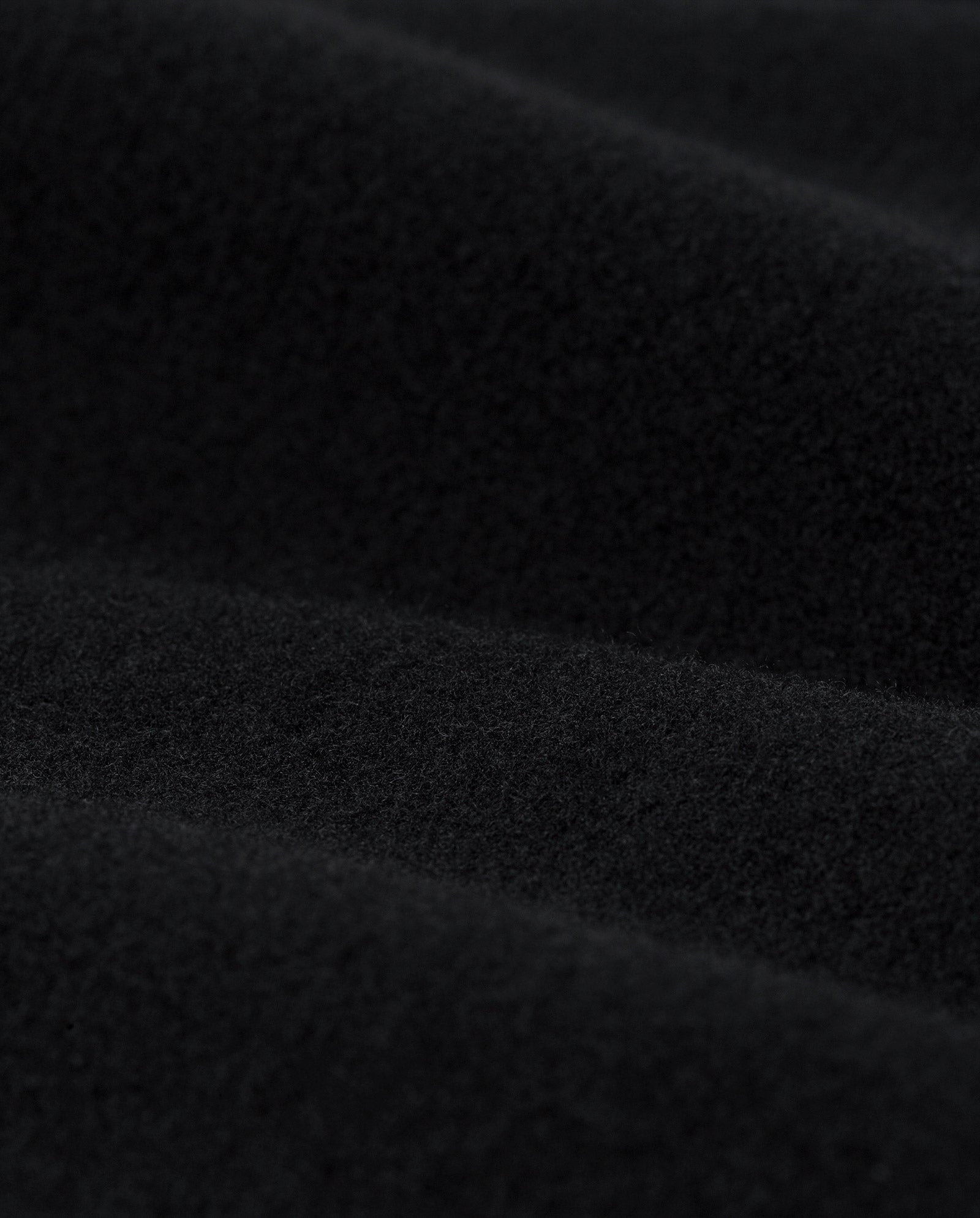 Close-up of black fleece fabric with a soft, textured surface and gentle folds, evoking the luxurious feel of the IVY OAK CANDELA Coat.