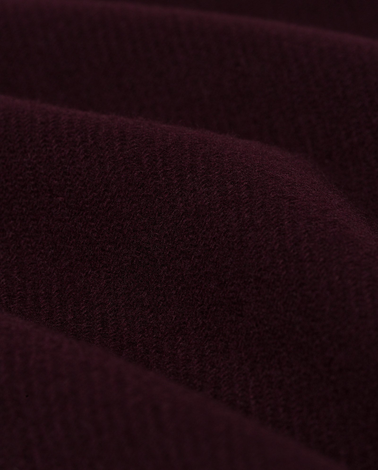 Close-up of the soft, dark burgundy wool fabric used in the IVY OAK CAYENNE Coat, featuring gentle wavy folds and textured surface—ideal for a loose-fitting, knee-length design.