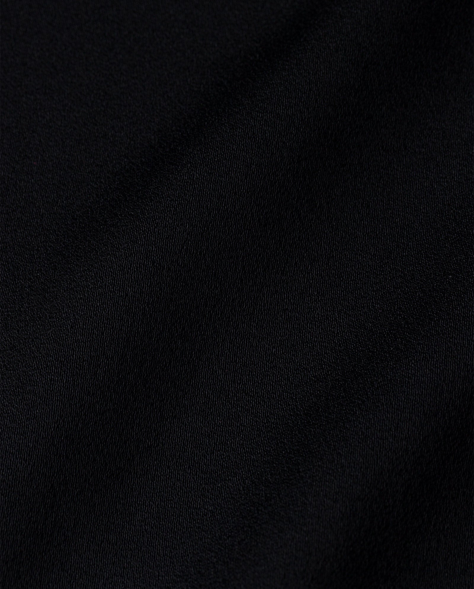 Close-up of the ELINOR Blouse by IVY OAK, featuring smooth black cotton with subtle folds and a textured surface.