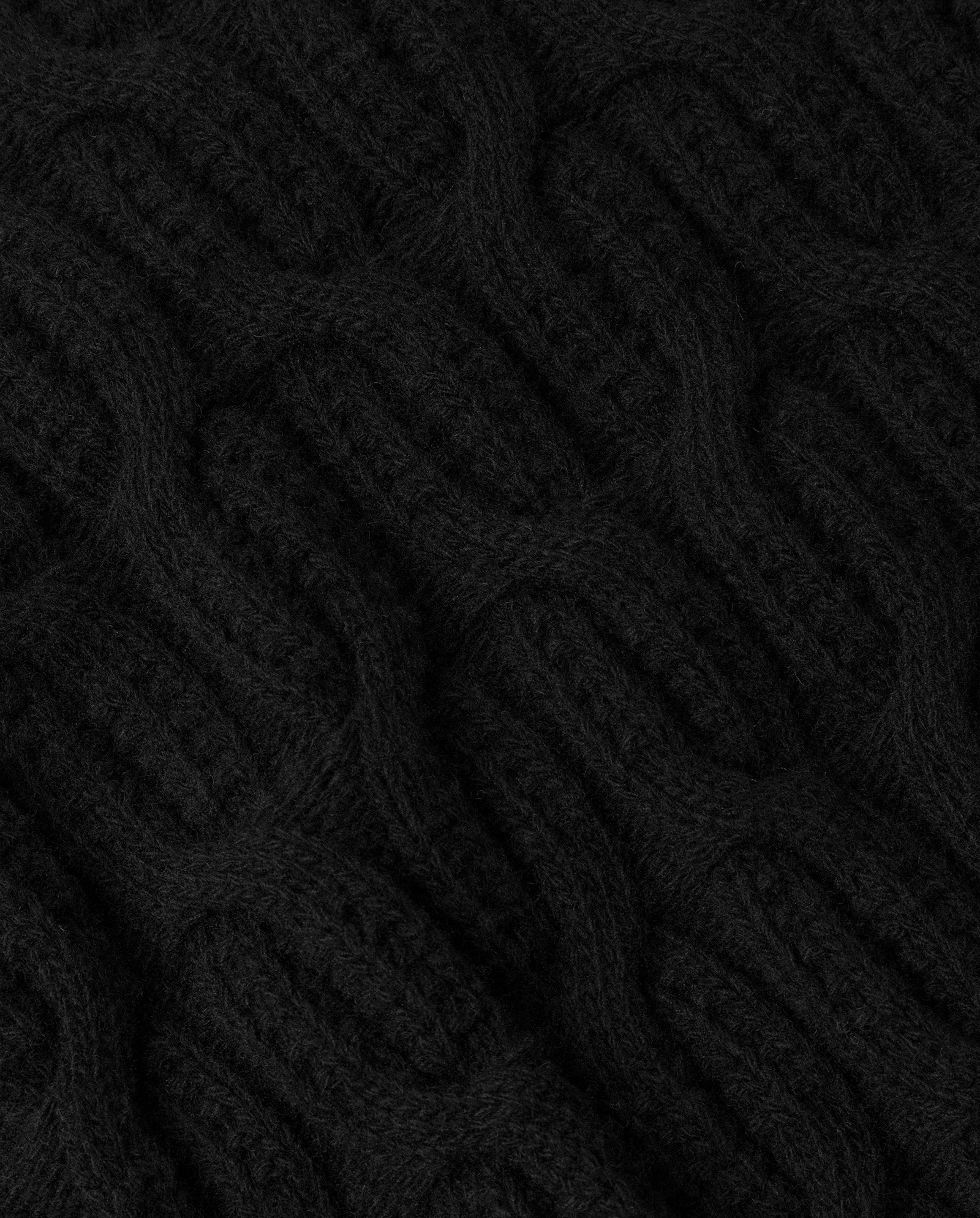 Close-up of the KLARINA Jumper by IVY OAK, showcasing black cable knit fabric with a textured, woven pattern in extrafine merino wool.