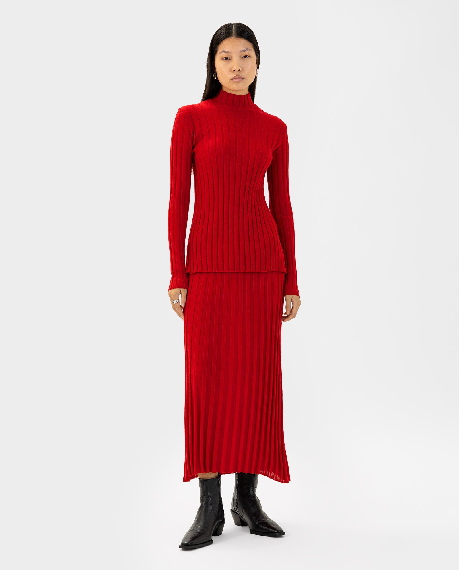 Woman wearing the IVY OAK KACY Jumper, a long-sleeve red ribbed dress with Rippstruktur, paired with black boots against a plain white background.