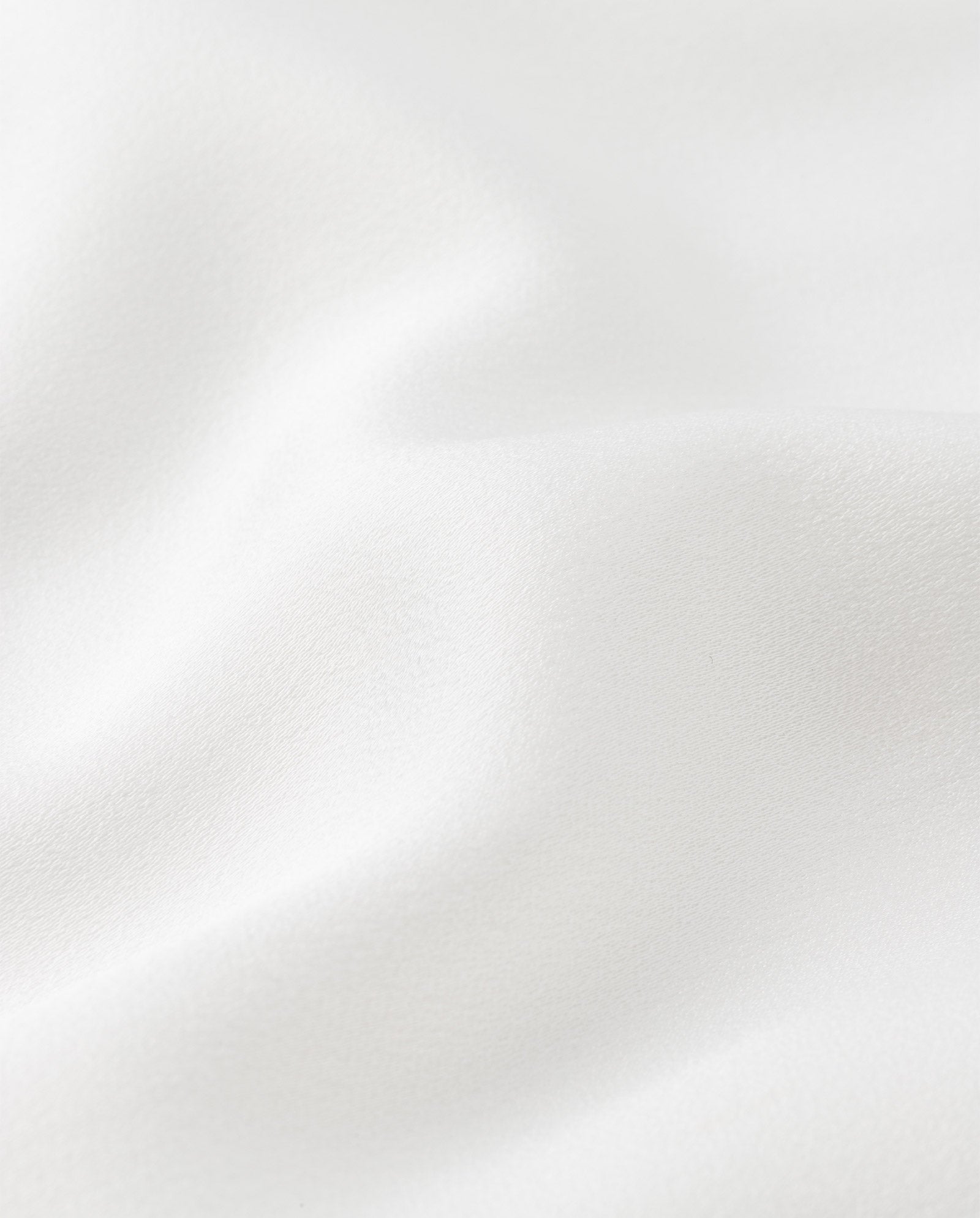 Close-up of the NONA Dress by IVY OAK, featuring smooth white satin fabric with gentle folds and a soft texture, highlighting delicate princess seams.