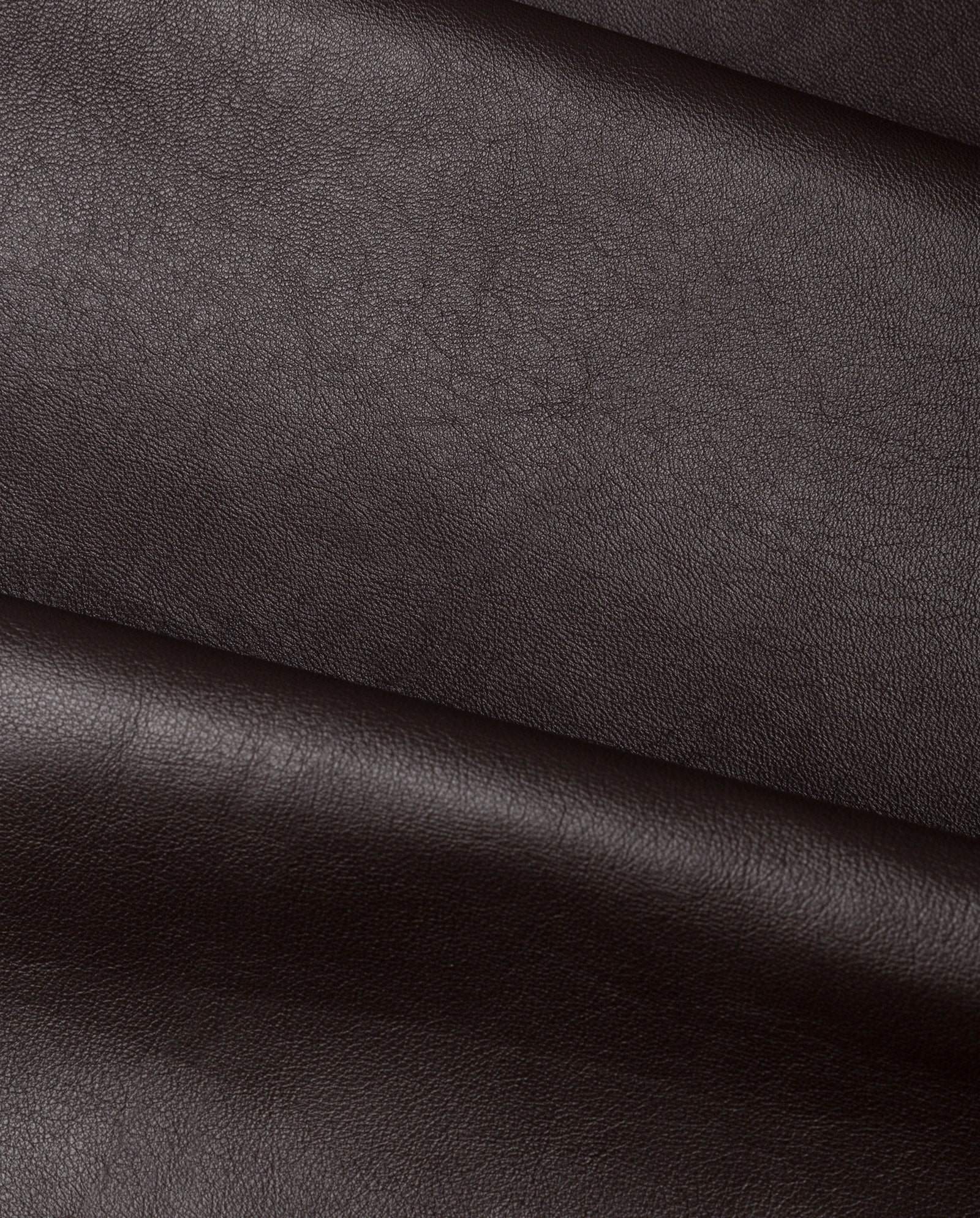 Close-up of the LIONNE Coat by IVY OAK, crafted from dark brown Lamb Nappa leather with a smooth, slightly textured surface and gentle folds.