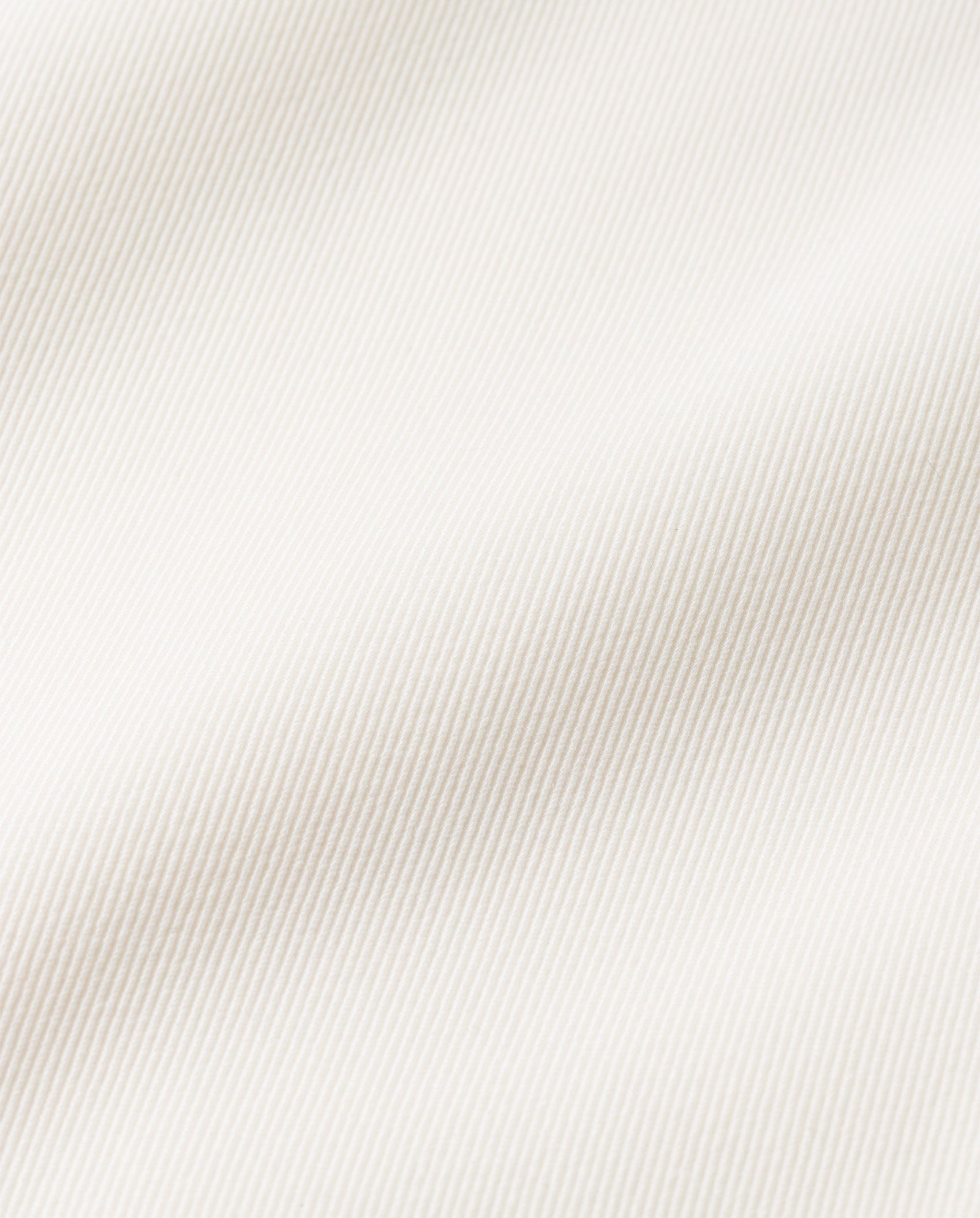 Close-up of the JIL ANN Coat by IVY OAK, featuring smooth white matt fabric with a subtle diagonal ribbed texture and gentle folds—ideal for a transformable style or chic blazer coat.