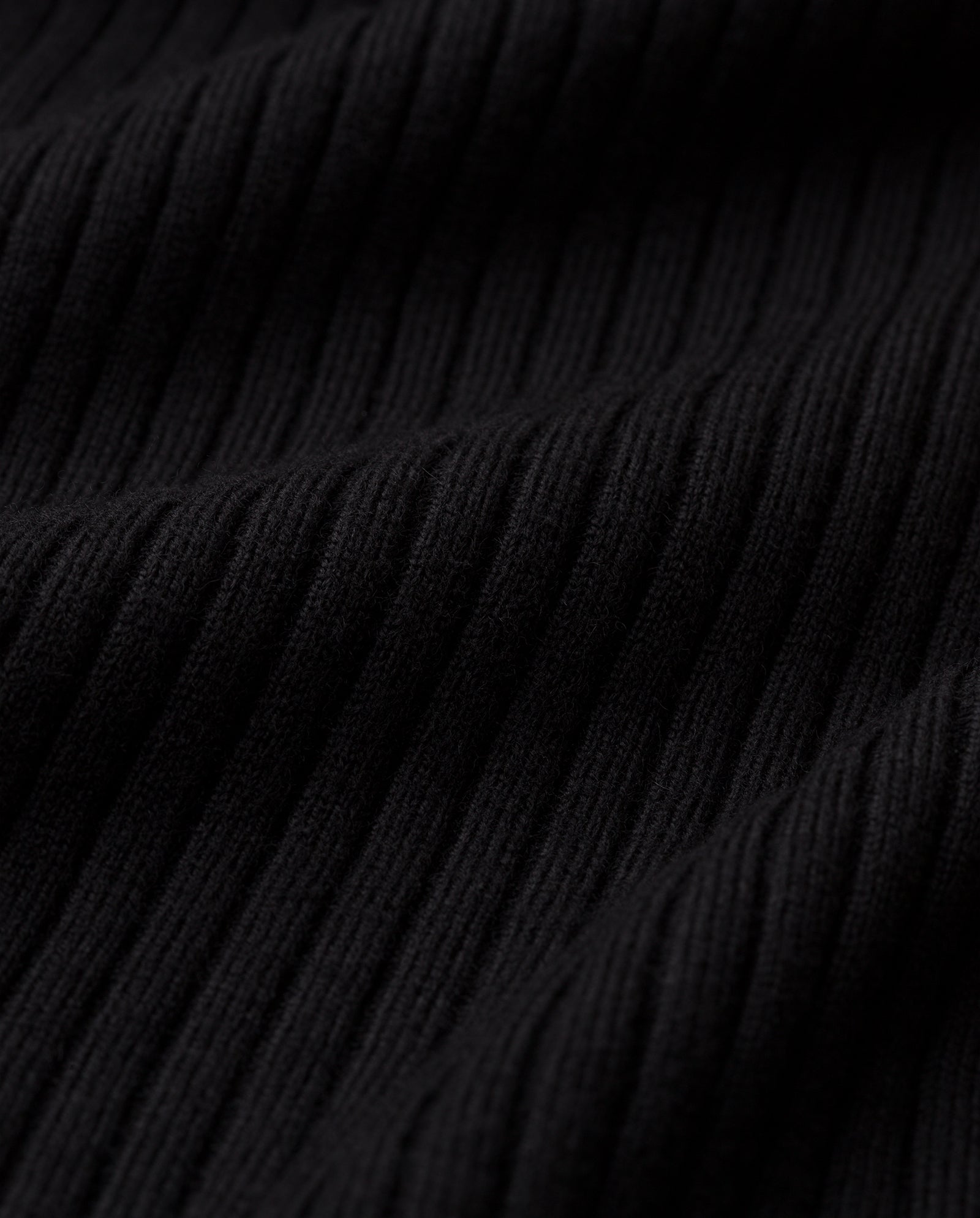 Close-up of the black ribbed fabric with vertical textured lines, highlighting the sleek design of the KARO Jumper by IVY OAK.