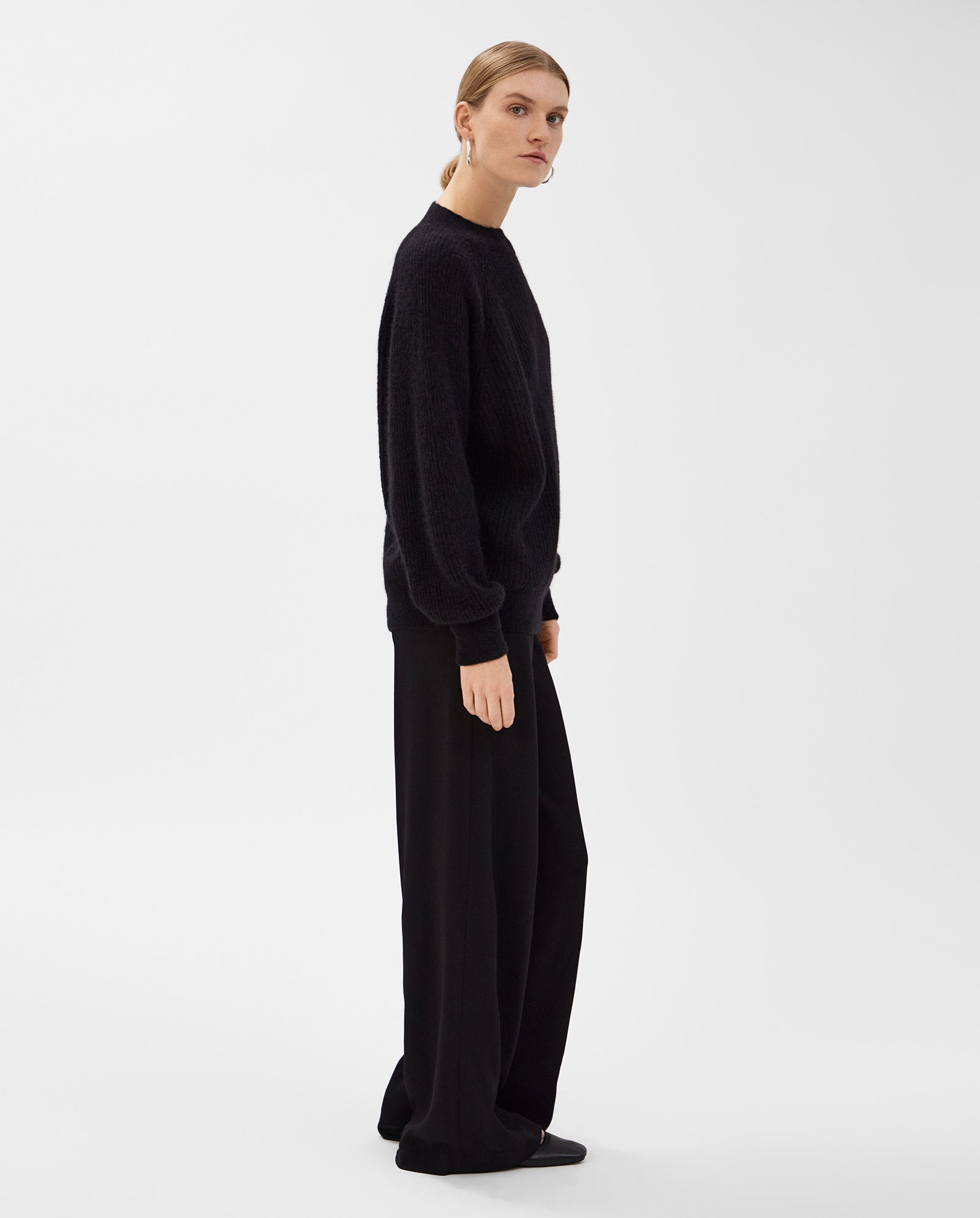 A woman wearing the IVY OAK KIRSTEN Jumper with raglan sleeves and wide-leg black pants stands sideways against a plain white background.