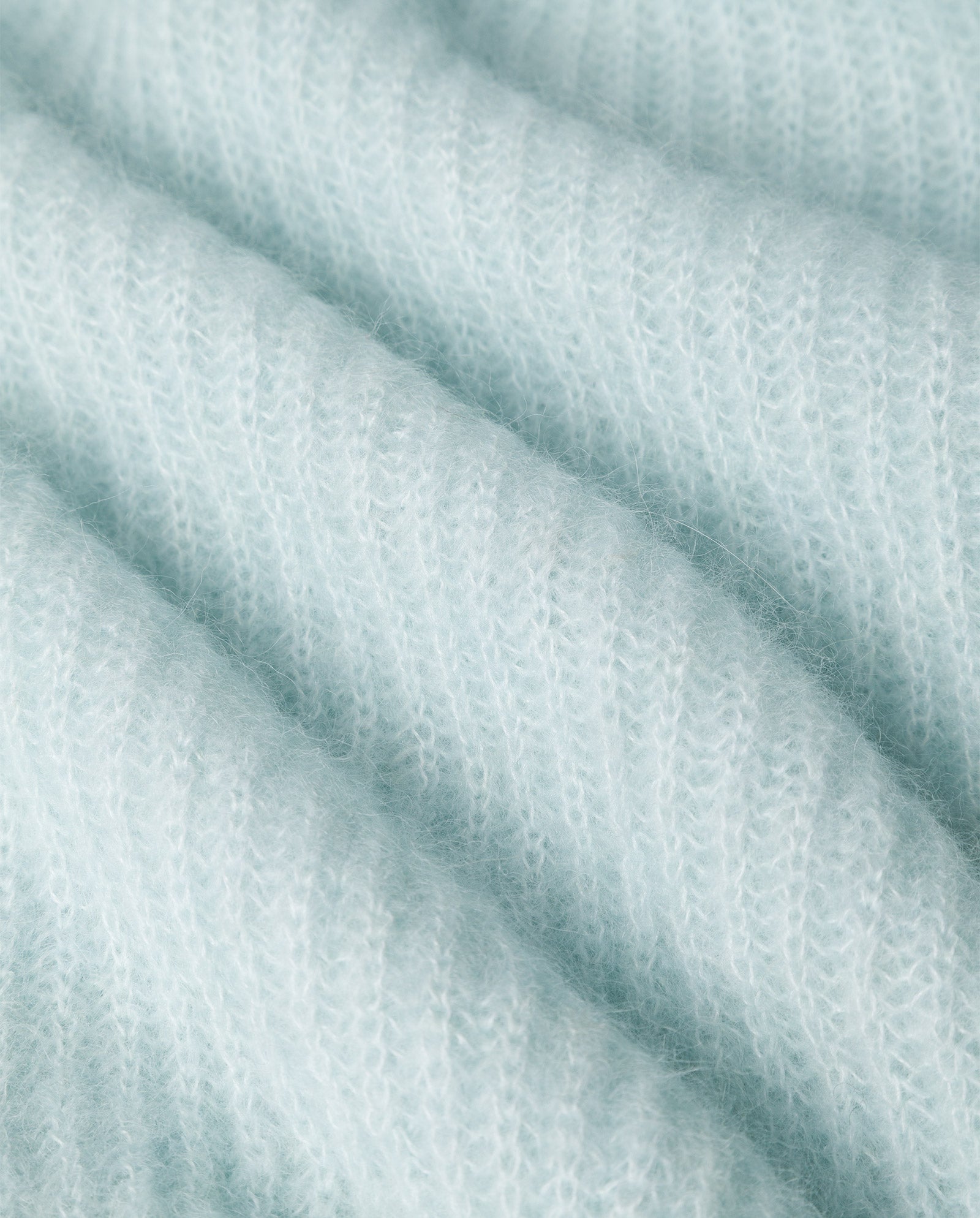 Close-up of light blue, ribbed knit fabric from the KIRSTEN Jumper by IVY OAK, crafted in a soft alpaca blend, highlighting its fuzzy texture and parallel ridges.