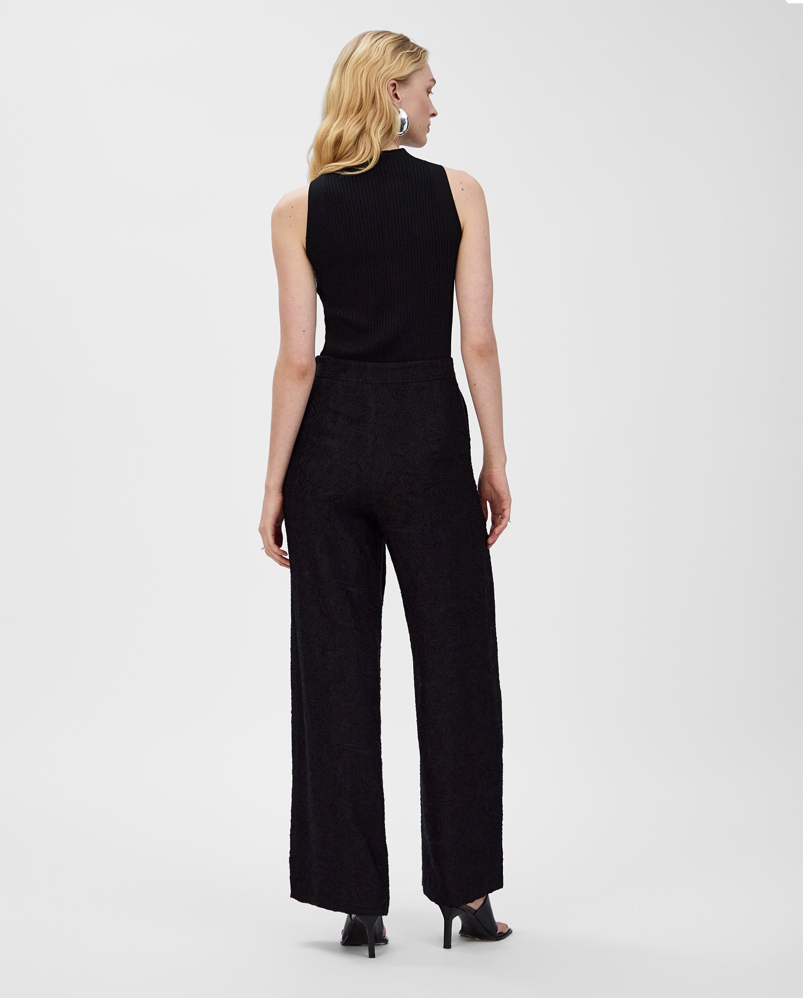 Woman facing away on a white background, wearing the IVY OAK KESSIE Top in black with matching black wide-leg pants.