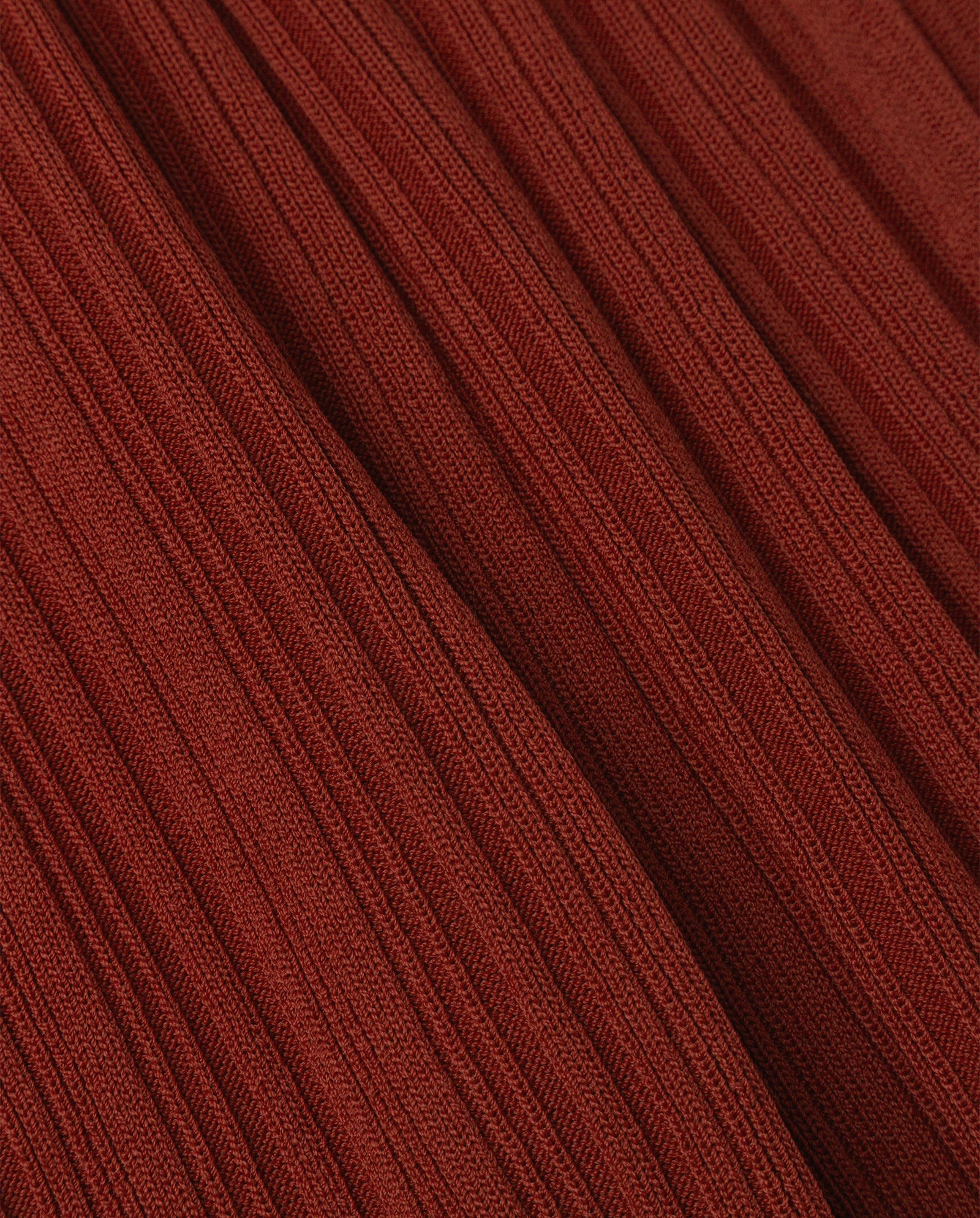 Close-up of ribbed, rust-colored knit fabric with vertical textured lines, featured on the figure-hugging KANDICE Dress by IVY OAK.
