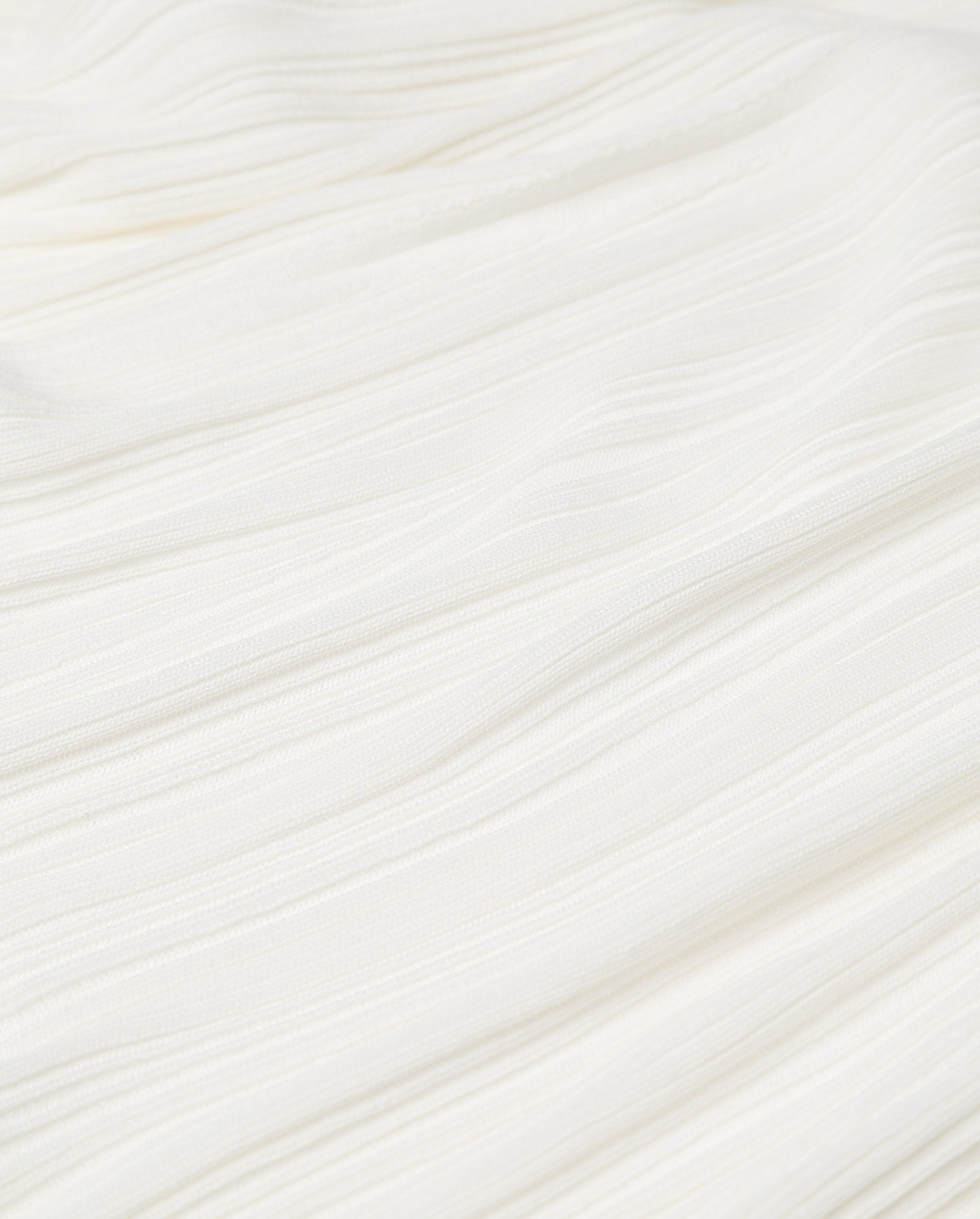 The KIERA Cardigan by IVY OAK features white textured fabric with an irregular knit, subtle horizontal lines, and gentle folds.