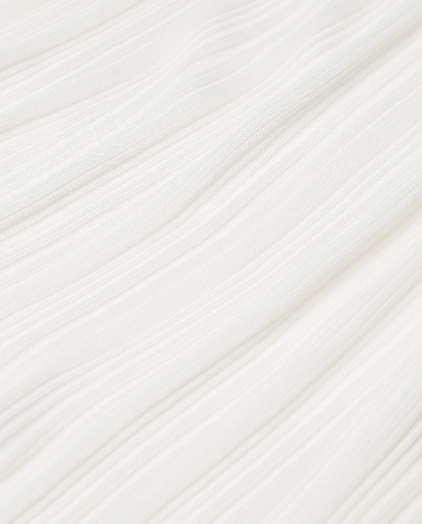Close-up of the white textured fabric of the IVY OAK KLOE Dress, featuring subtle horizontal lines and gentle folds, evoking the elegant sleeve of this softly flared viscose wrap silhouette.