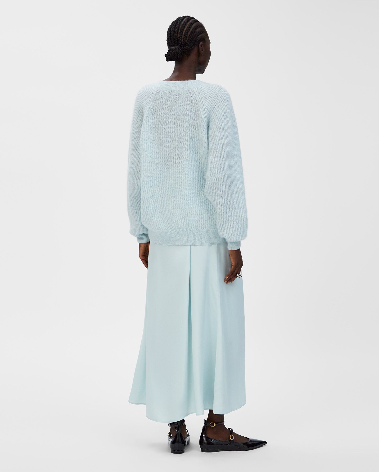 A person wearing the IVY OAK KEONA ANN Cardigan in light blue, paired with a matching skirt, stands against a plain white background and is seen from behind.