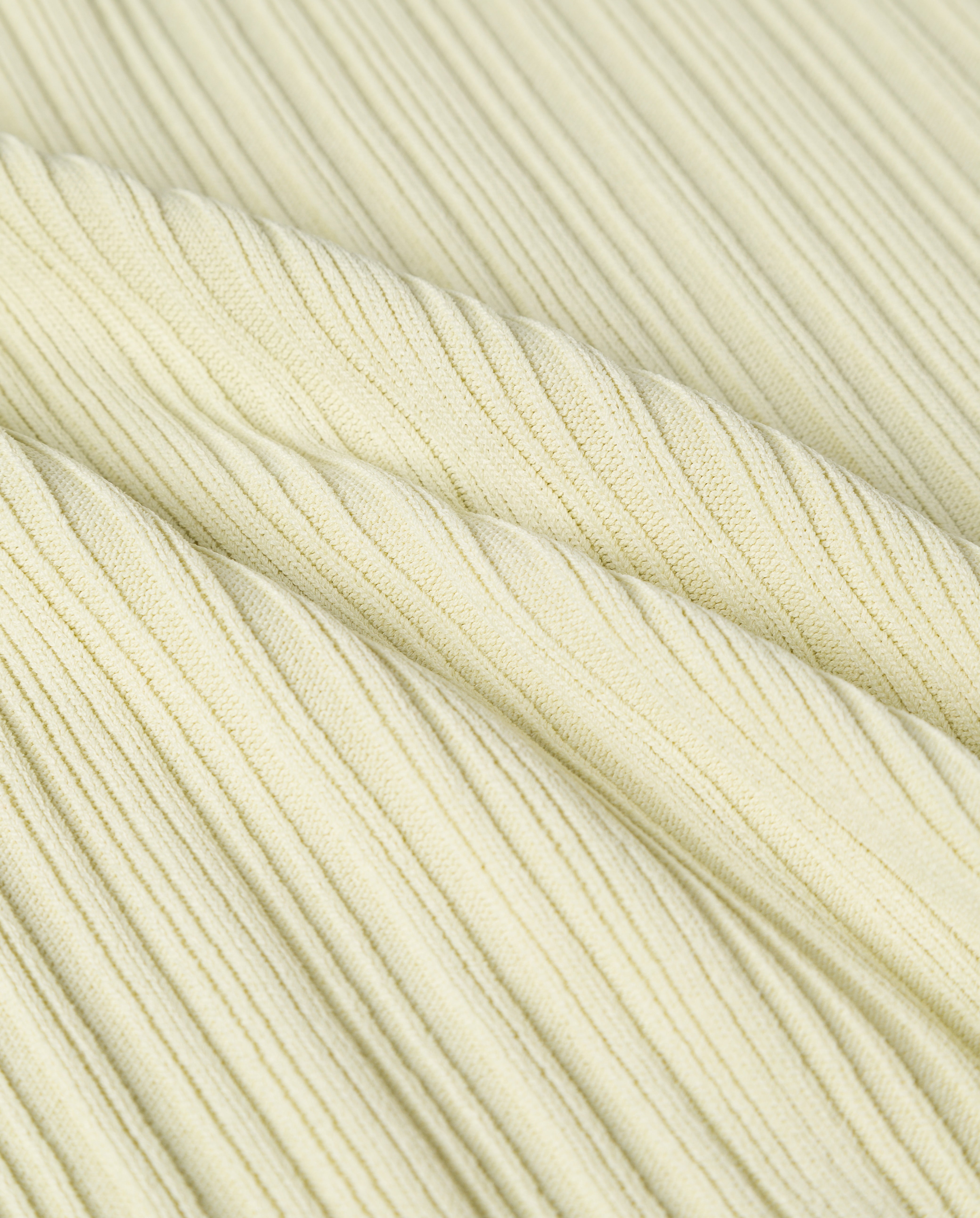 Close-up of the KYM Top by IVY OAK, featuring light yellow, stretchy knit fabric with diagonal textured lines and soft folds—ideal for a deep V-neckline style.