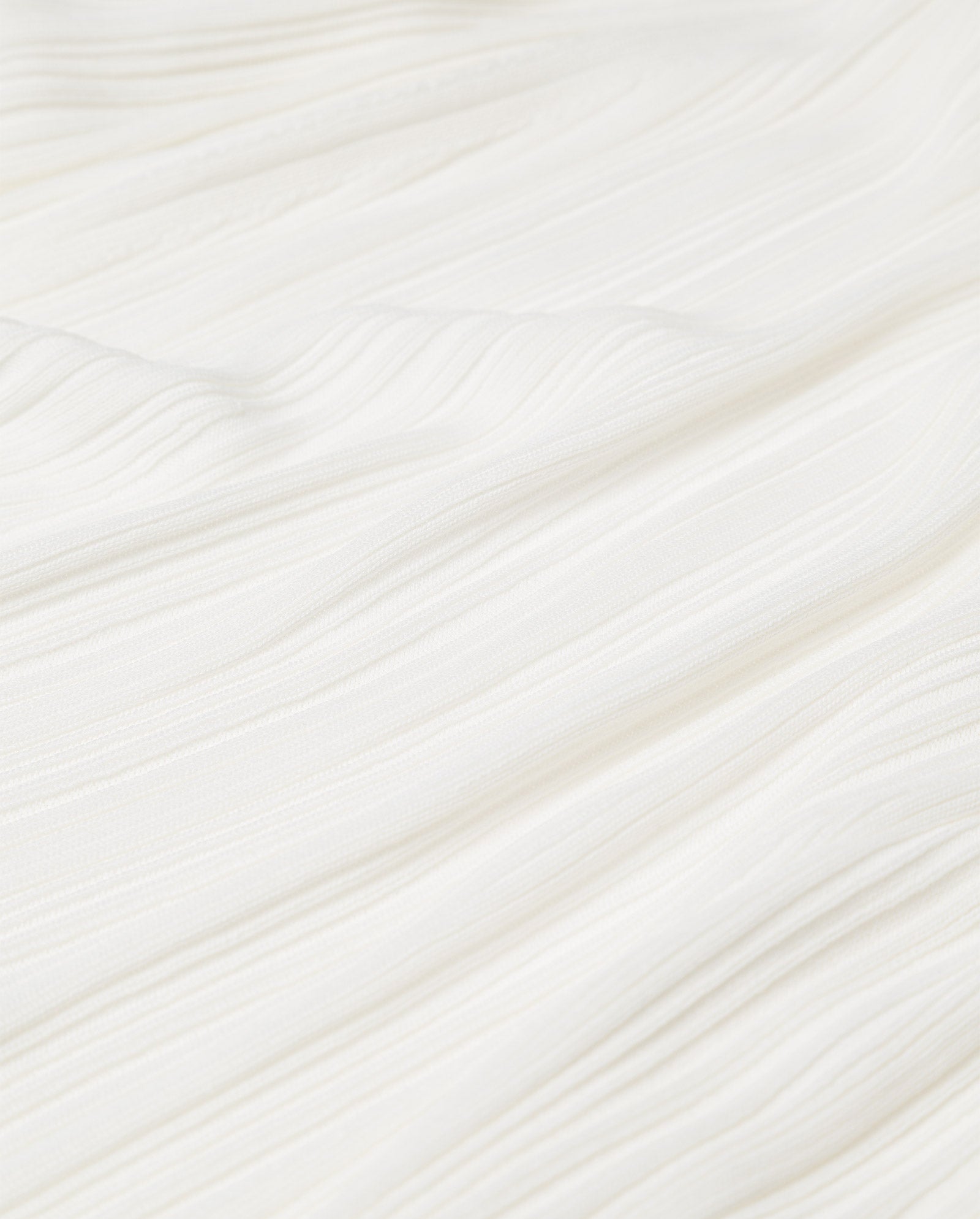 Close-up of the KYM Top by IVY OAK, featuring white textured stretchy knit fabric with subtle diagonal wavy lines.