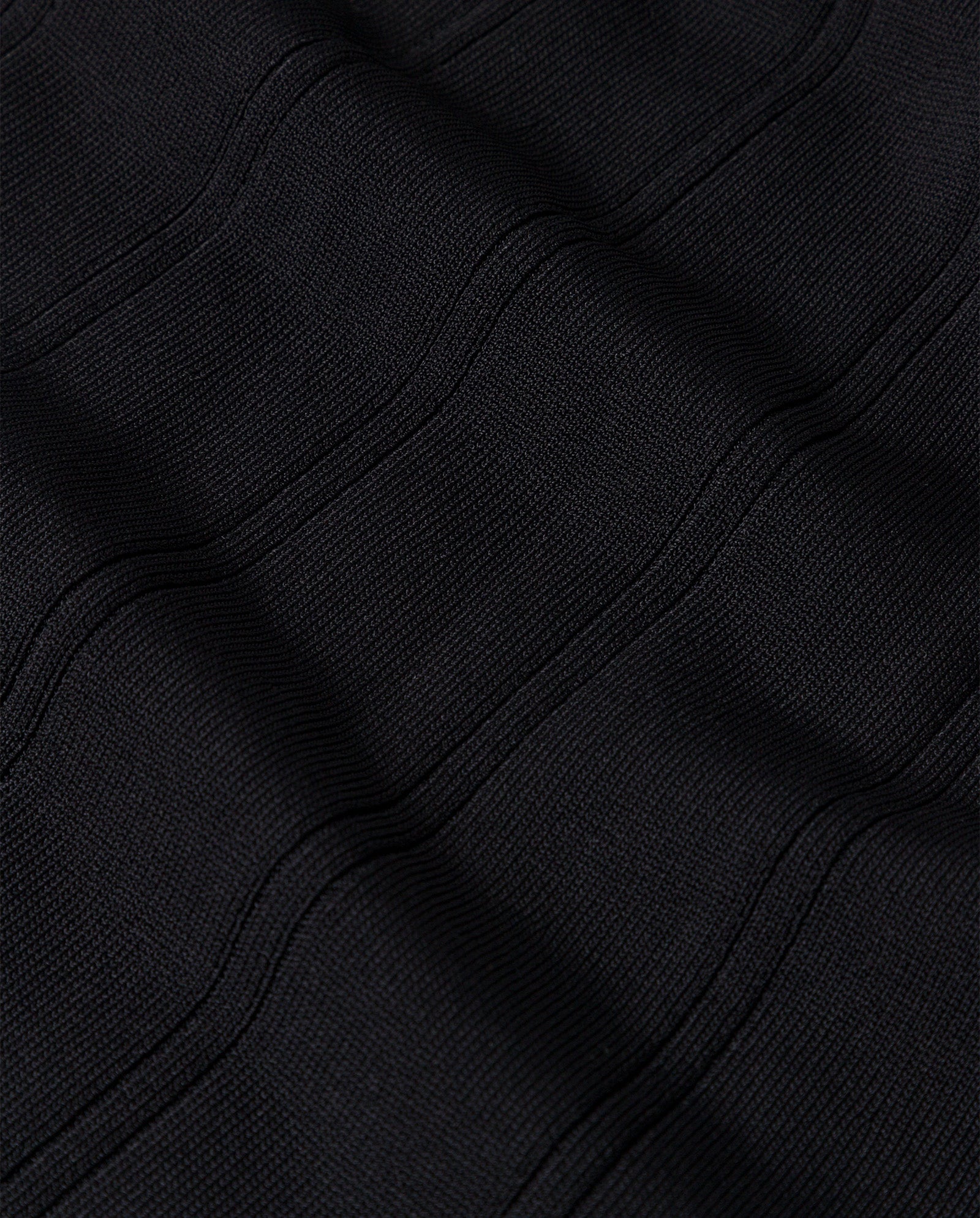 Close-up of the KOURTNEY Dress by IVY OAK shows black textured fabric with subtle, wavy horizontal stitches that create a pleated look, typical of a body-hugging viscose knit dress.