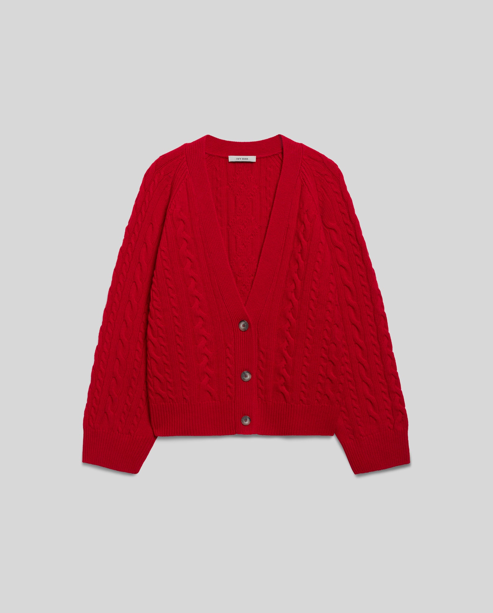 The IVY OAK KYMBERLY Cardigan is a red cable-knit design with a deep V-neck, three buttons, and a relaxed fit, shown against a light gray background.