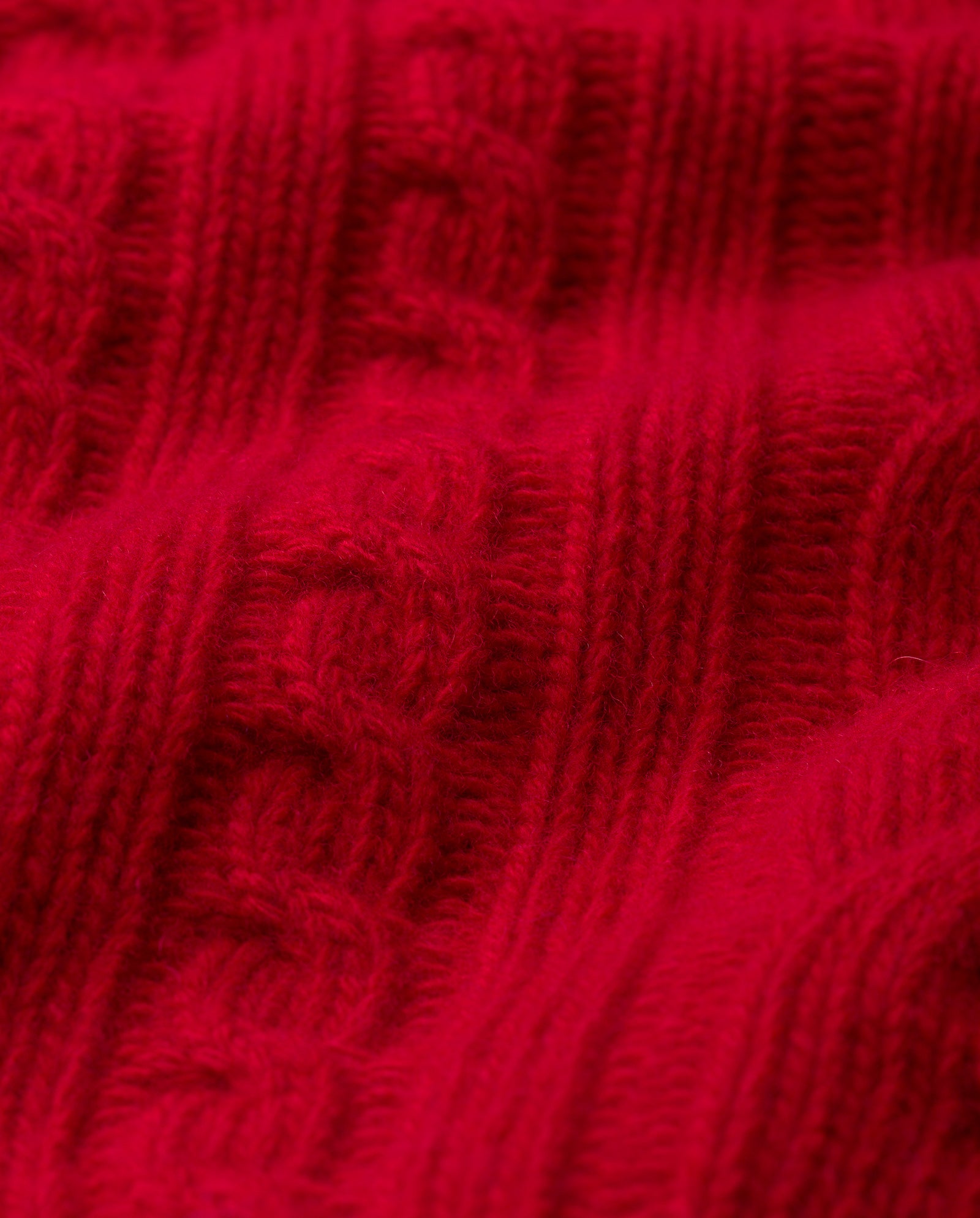 Close-up of red knitted fabric with a cable pattern and ribbed texture from the IVY OAK KYMBERLY Cardigan, perfect for creating a stylish deep v-neck look.