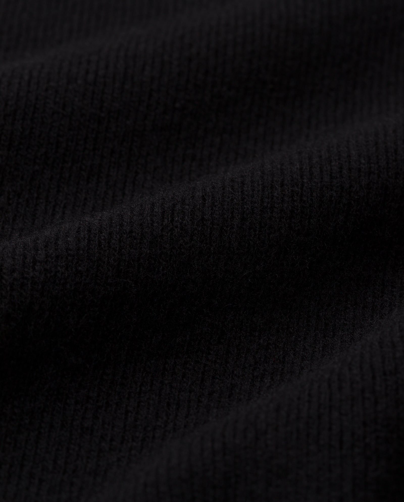 Close-up of the KAREEN ROSE Jumper by IVY OAK, featuring black ribbed Merino wool fabric with soft folds and visible texture.